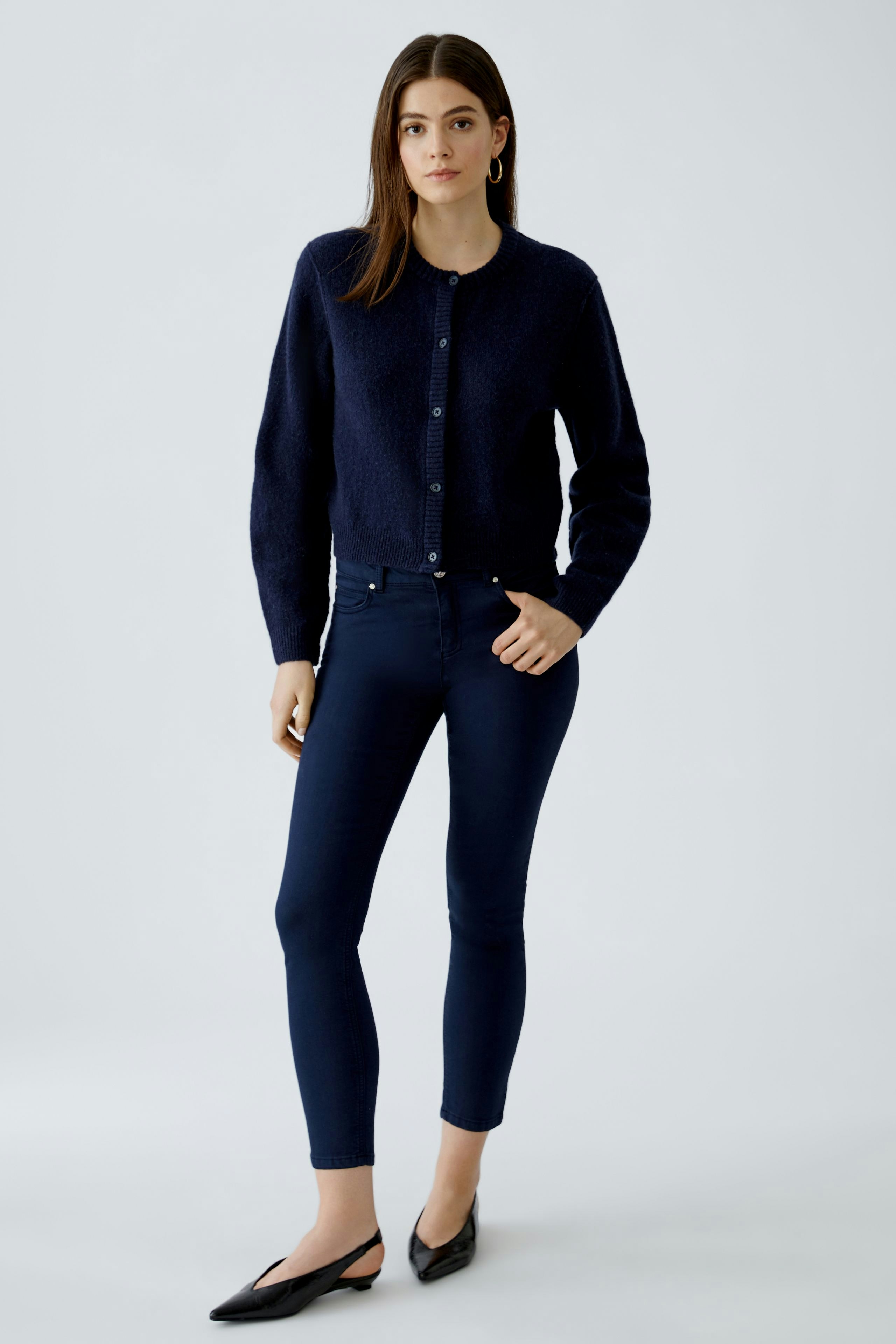 Casual women's cardigan: A woman in a navy knitted cardigan with buttons, paired with fitted jeans.