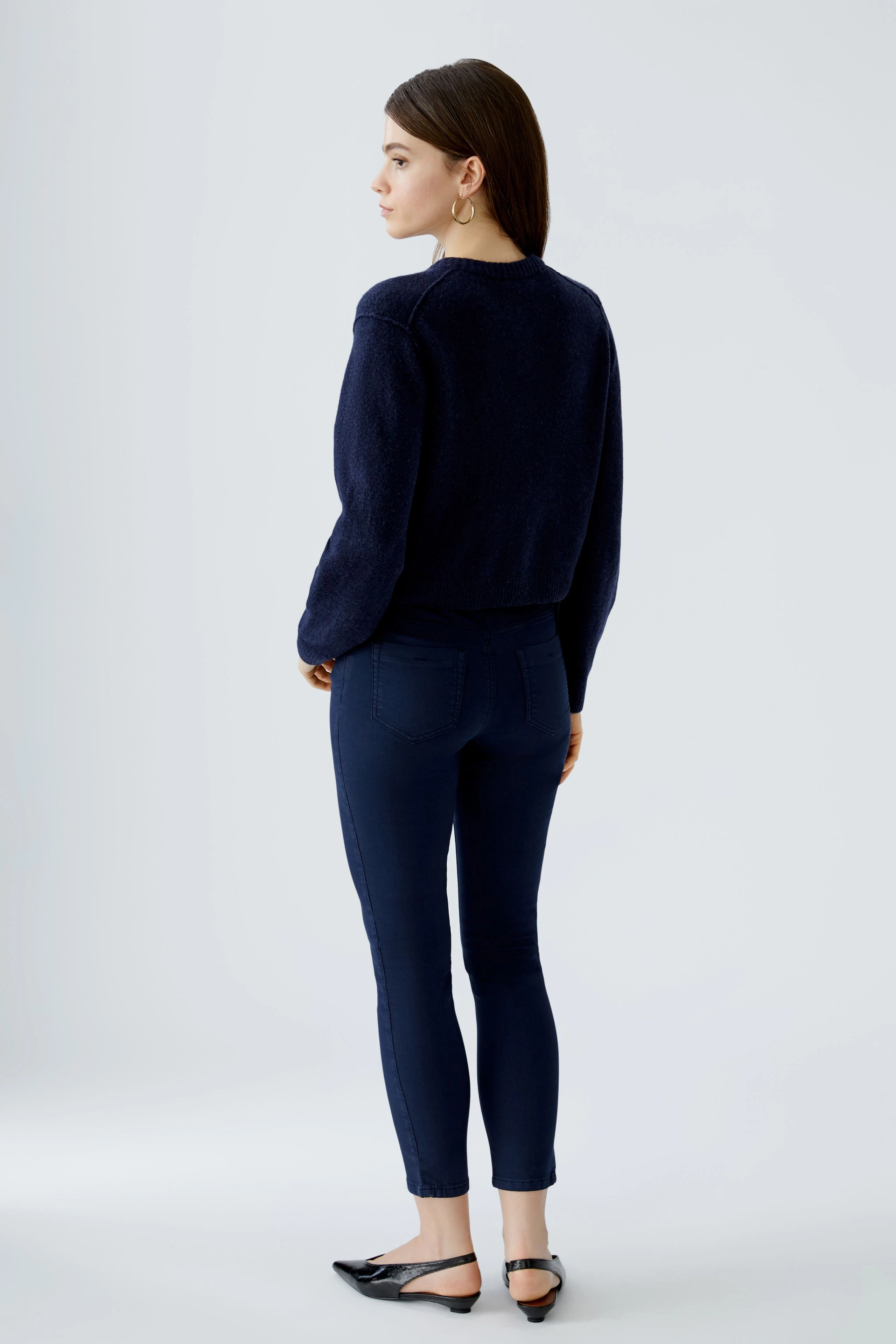 Damen-Strickjacke: Frau in dunkelblauer Strickjacke mit lässigem Schnitt und bequemen Jeans.