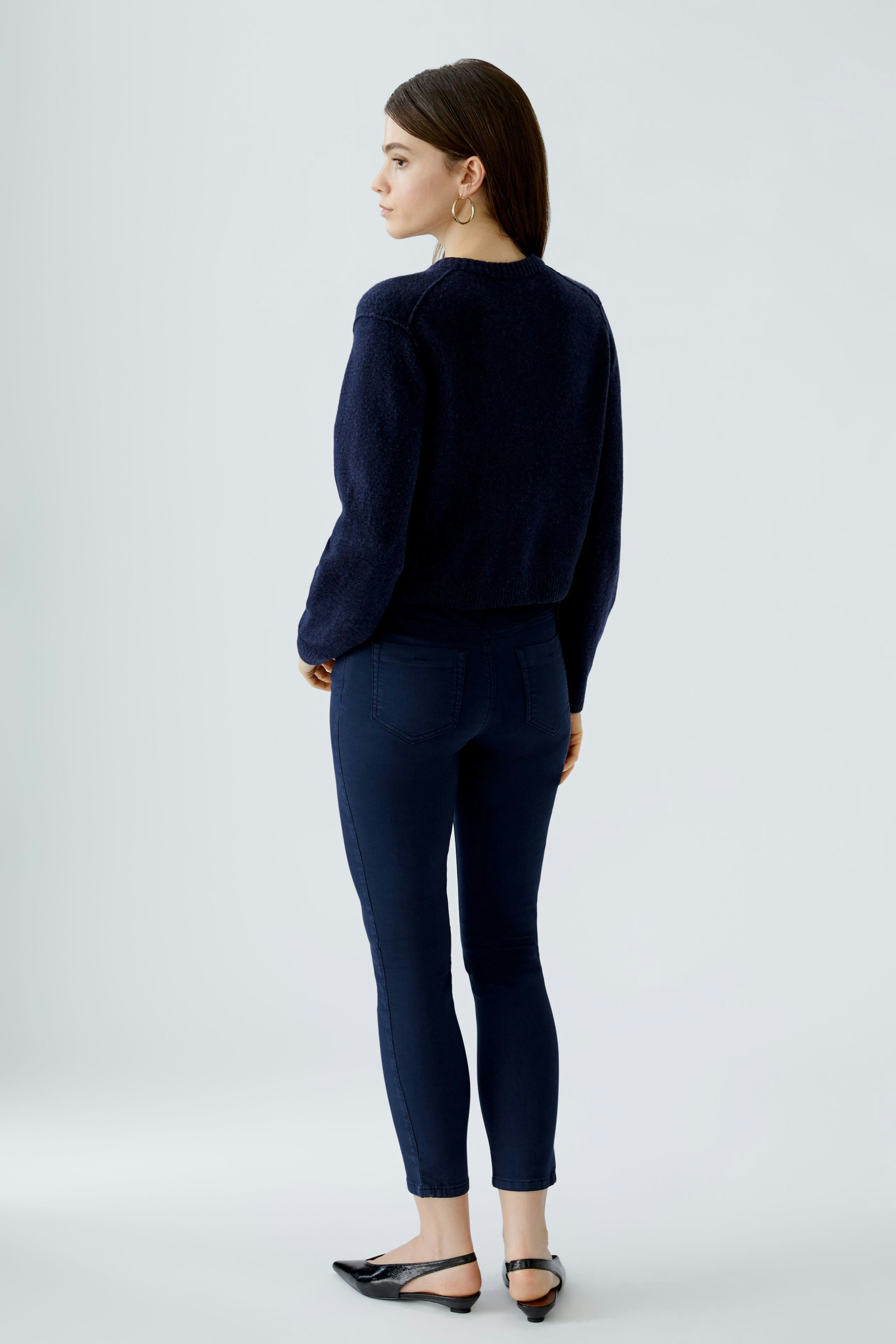 Casual women's cardigan: A woman in a navy cardigan with a relaxed fit, paired with dark jeans.