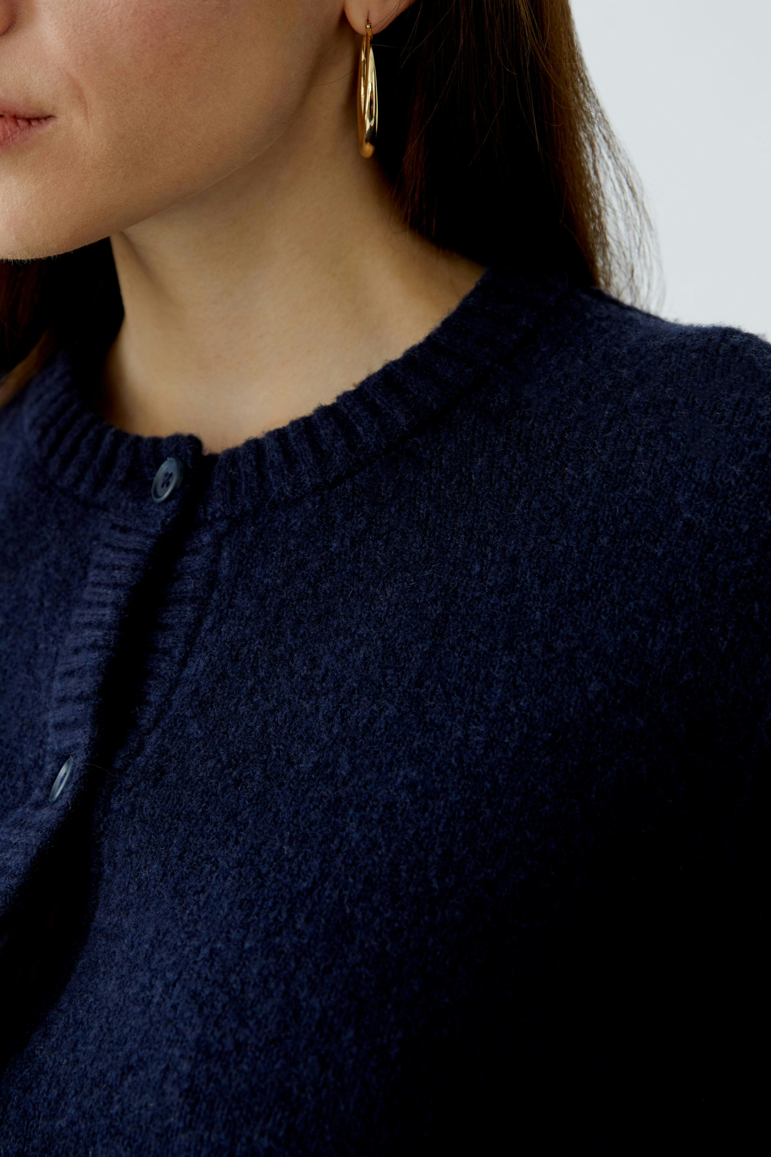 Casual women's cardigan: Close-up of a woman wearing a navy blue cardigan with a round neckline.