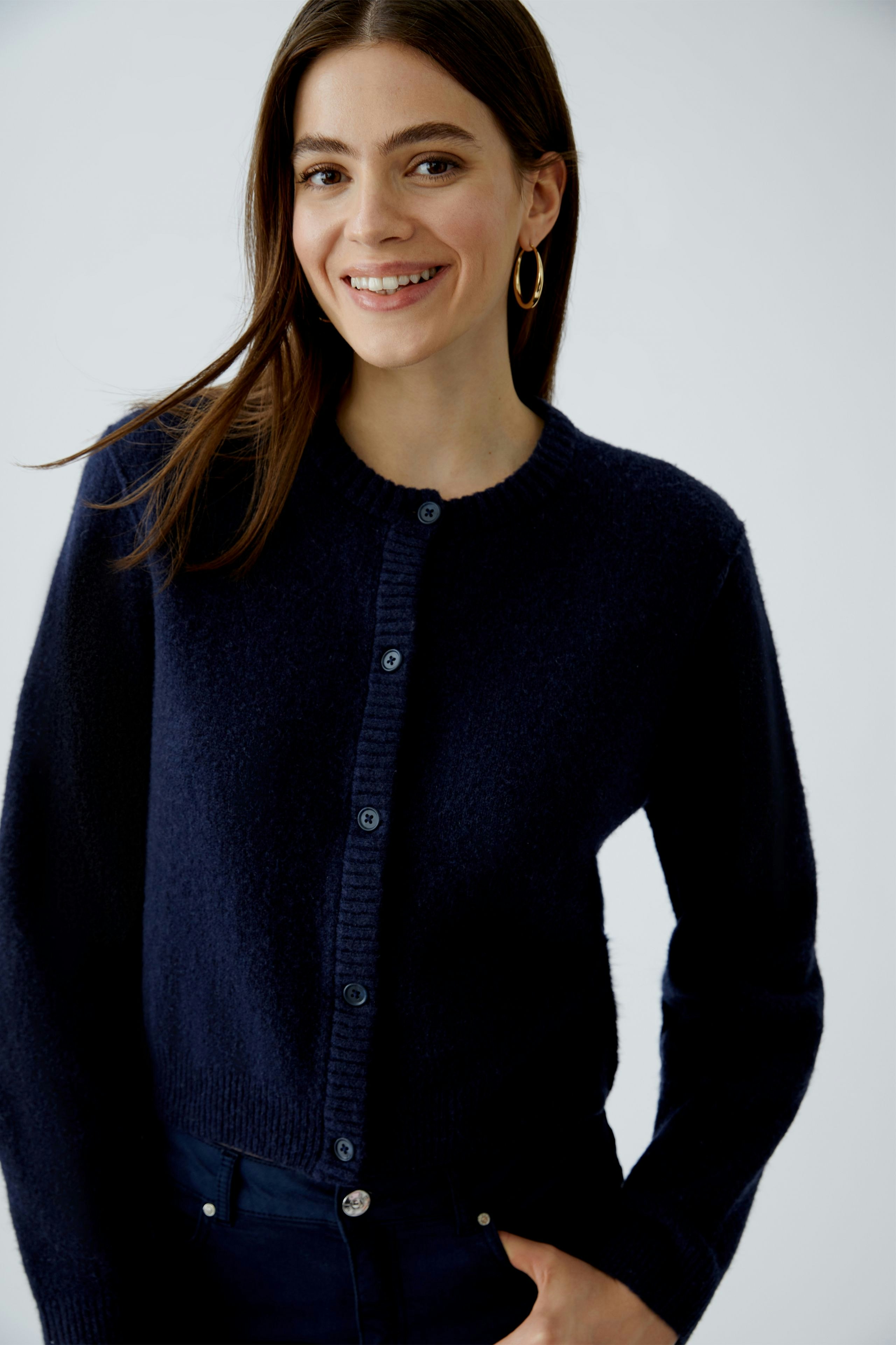 Casual women's cardigan: Smiling woman in a navy cardigan with buttons, paired with dark jeans.
