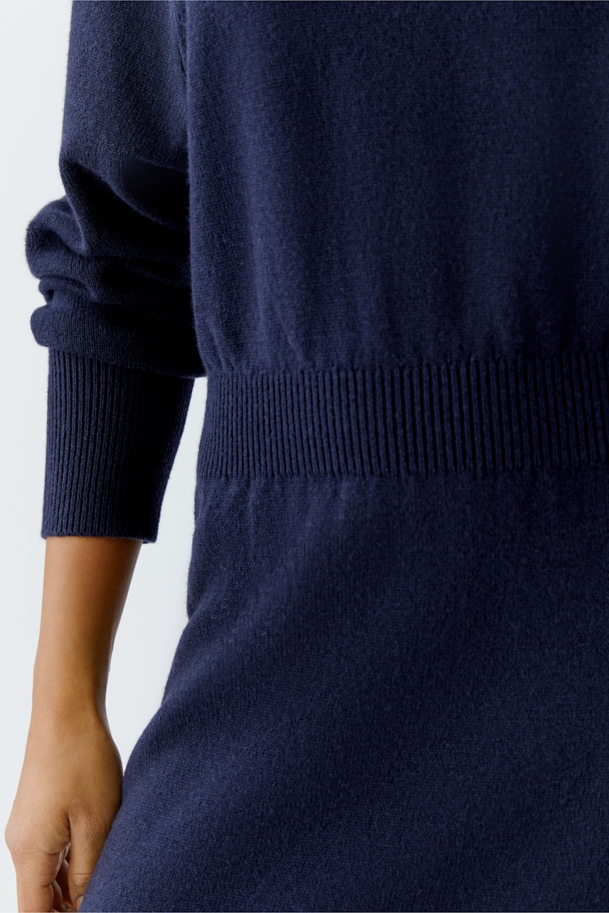 Damen-Strickkleid: Frau in einem dunkelblauen Strickkleid mit elastischem Bund und lässigem Schnitt.