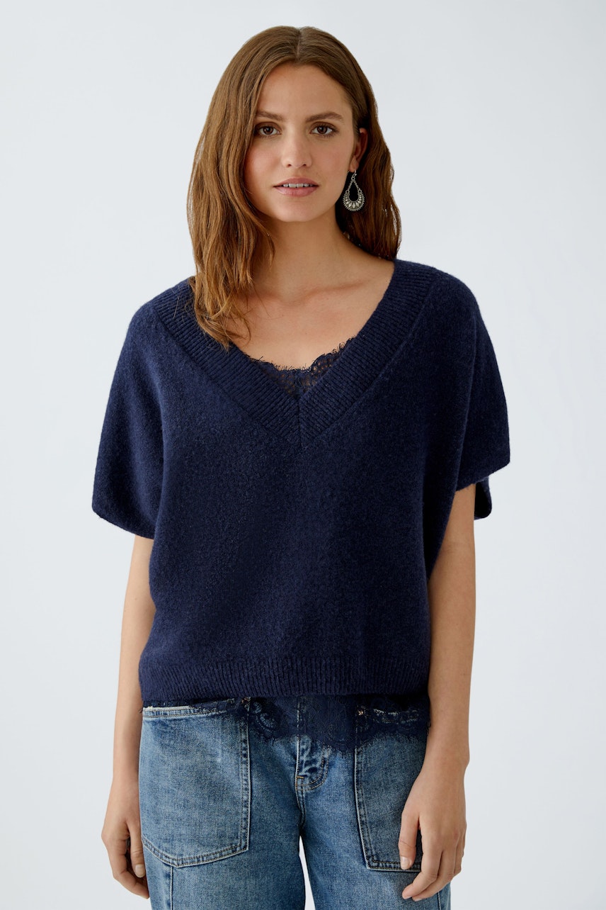 Casual women's pullover: A woman in a navy short-sleeve pullover with a V-neck and relaxed fit.