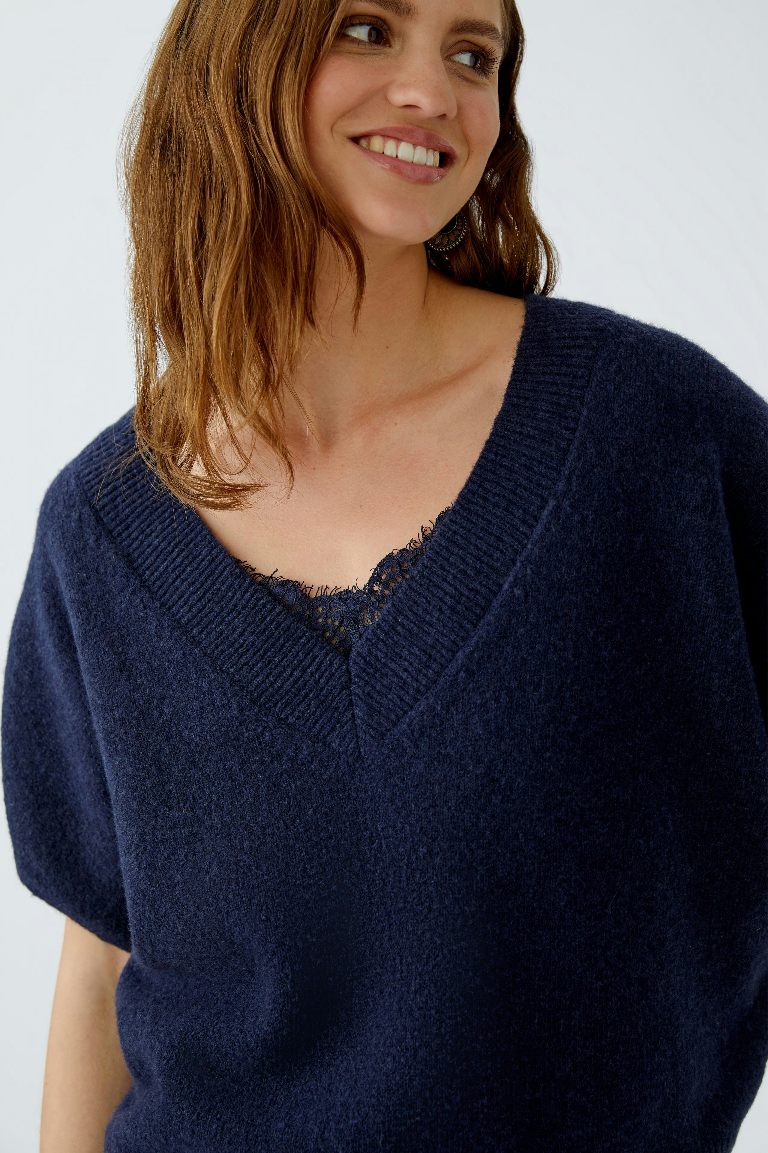 Casual women's pullover: Smiling woman in a navy oversized pullover with a deep V-neck.