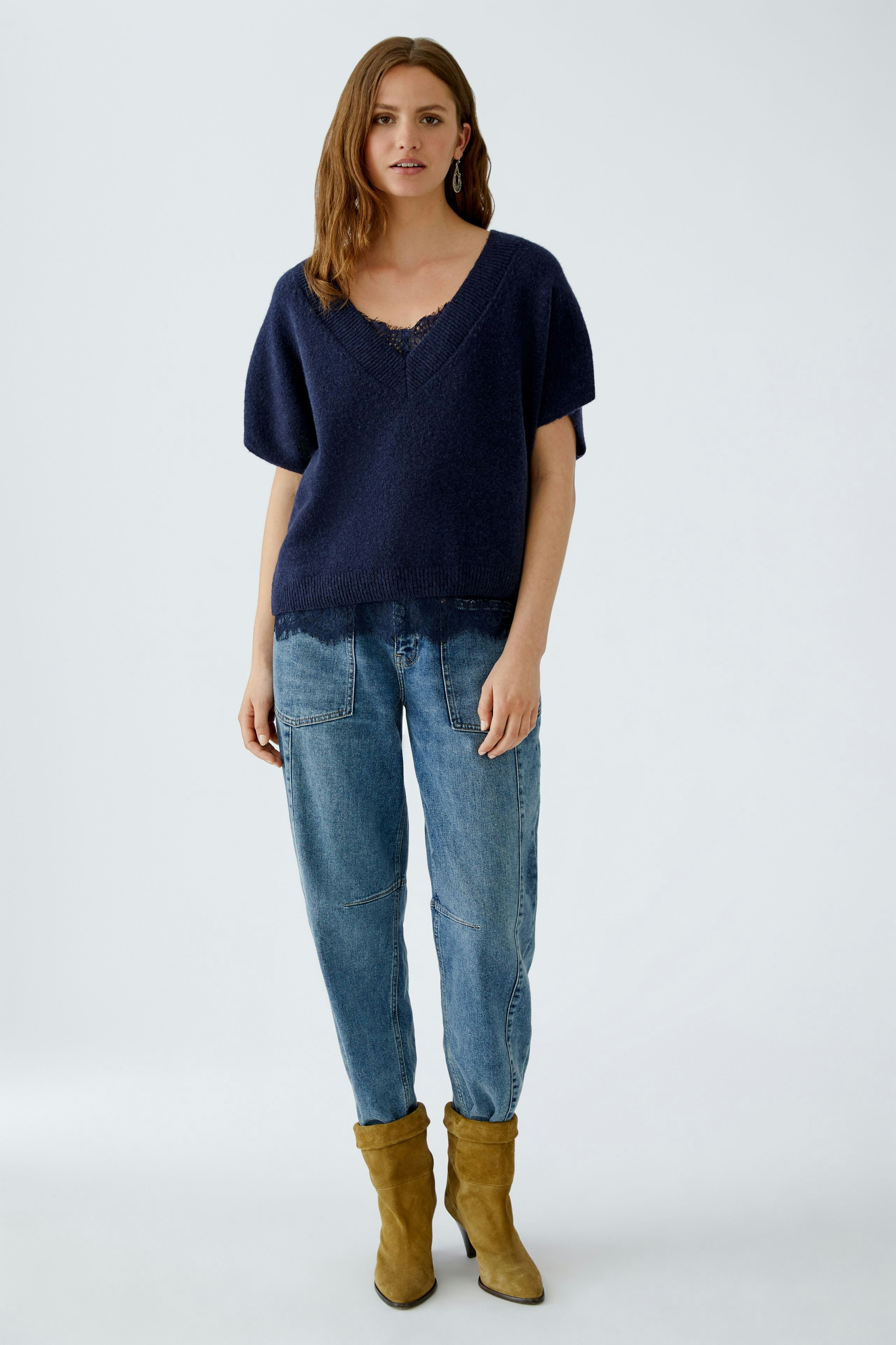 Casual women's pullover: A woman in a navy knitted pullover paired with relaxed jeans and stylish boots.