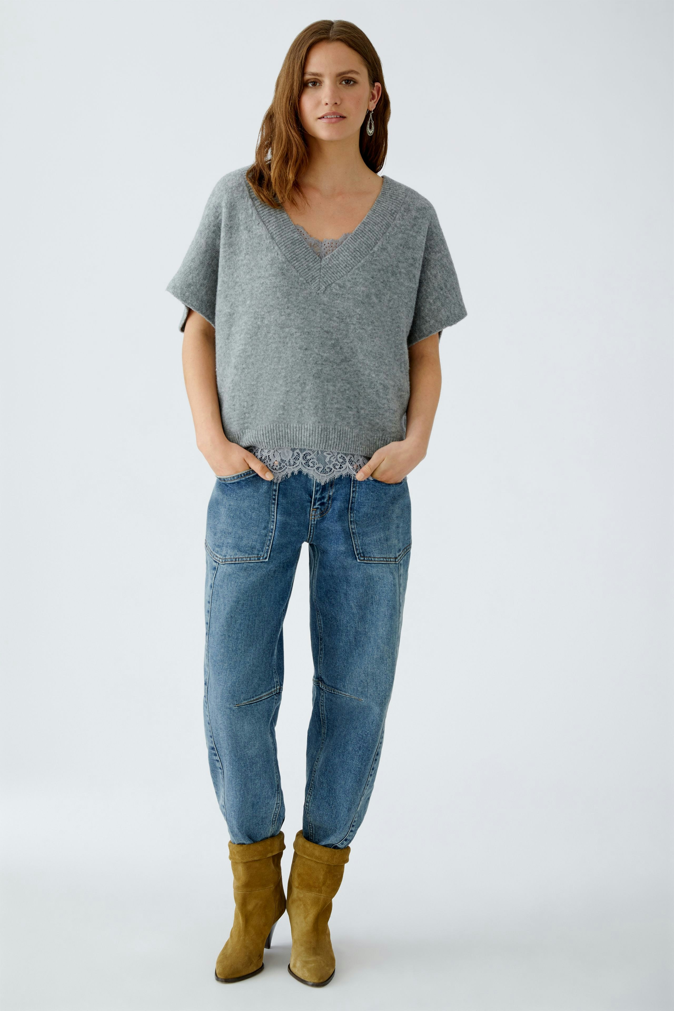 Bequemer Damen-Pullover: Frau in grauem Pullunder mit V-Ausschnitt und lässigen Jeans.