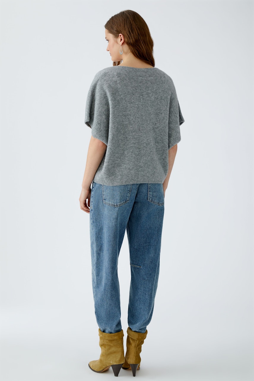 Damen-Pullover: Frau in grauem, lässigem Pullunder mit weitem Schnitt und bequemen Jeans.