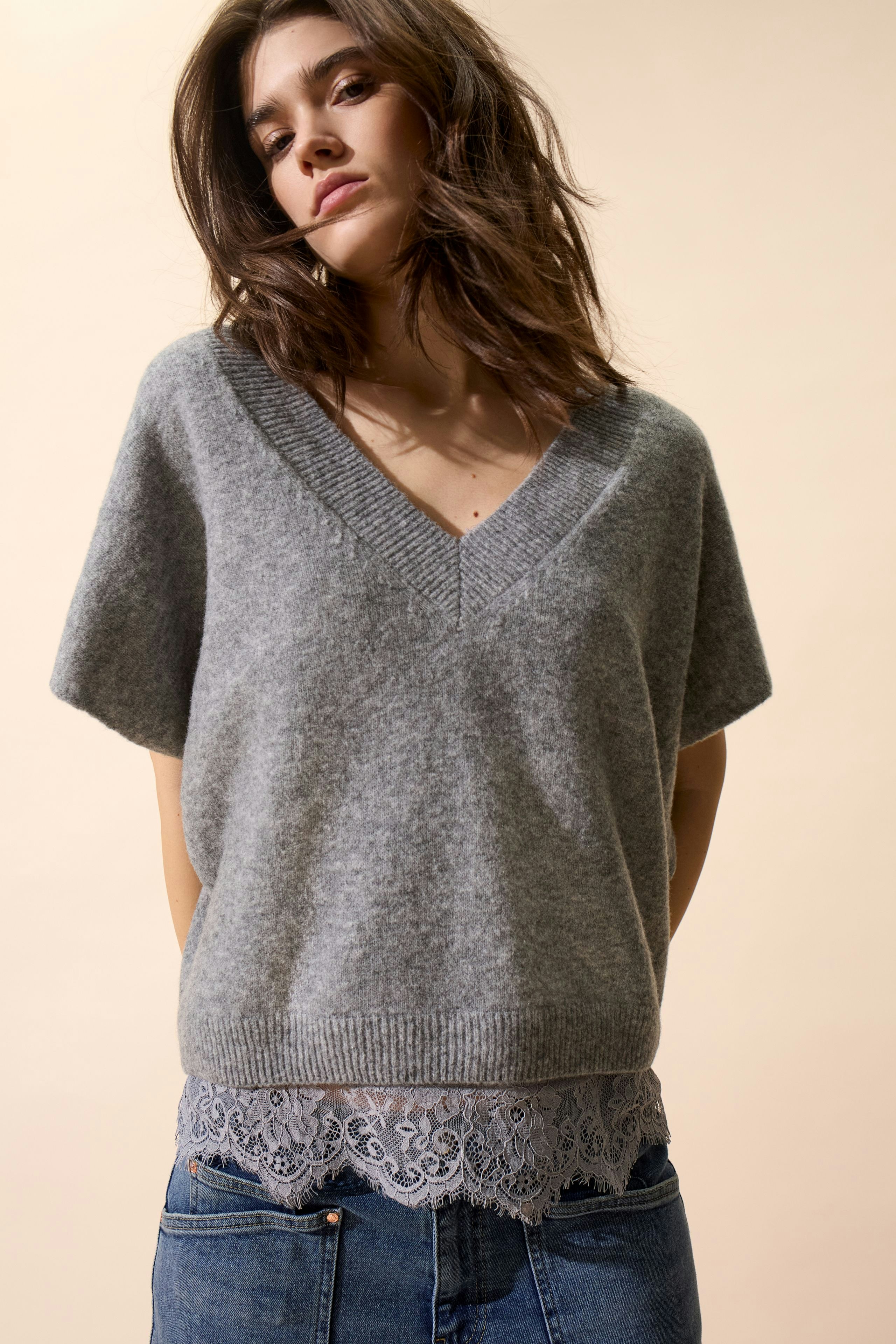 Bequemer Damen-Pulunder in Grau mit V-Ausschnitt und Spitzenabschluss, lässig kombiniert mit Jeans.