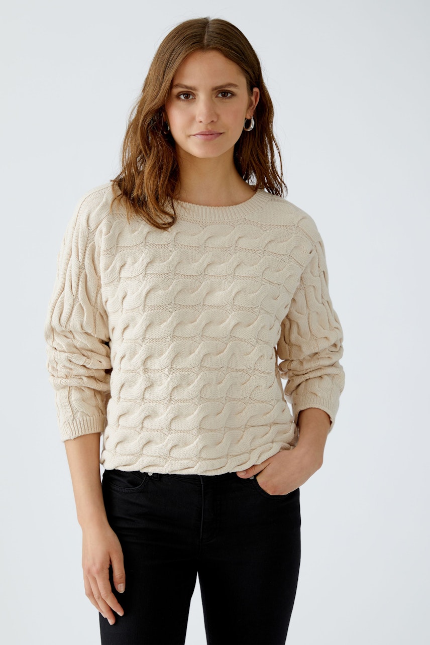 Casual women's pullover: A woman in a light beige textured pullover with relaxed fit and black jeans.