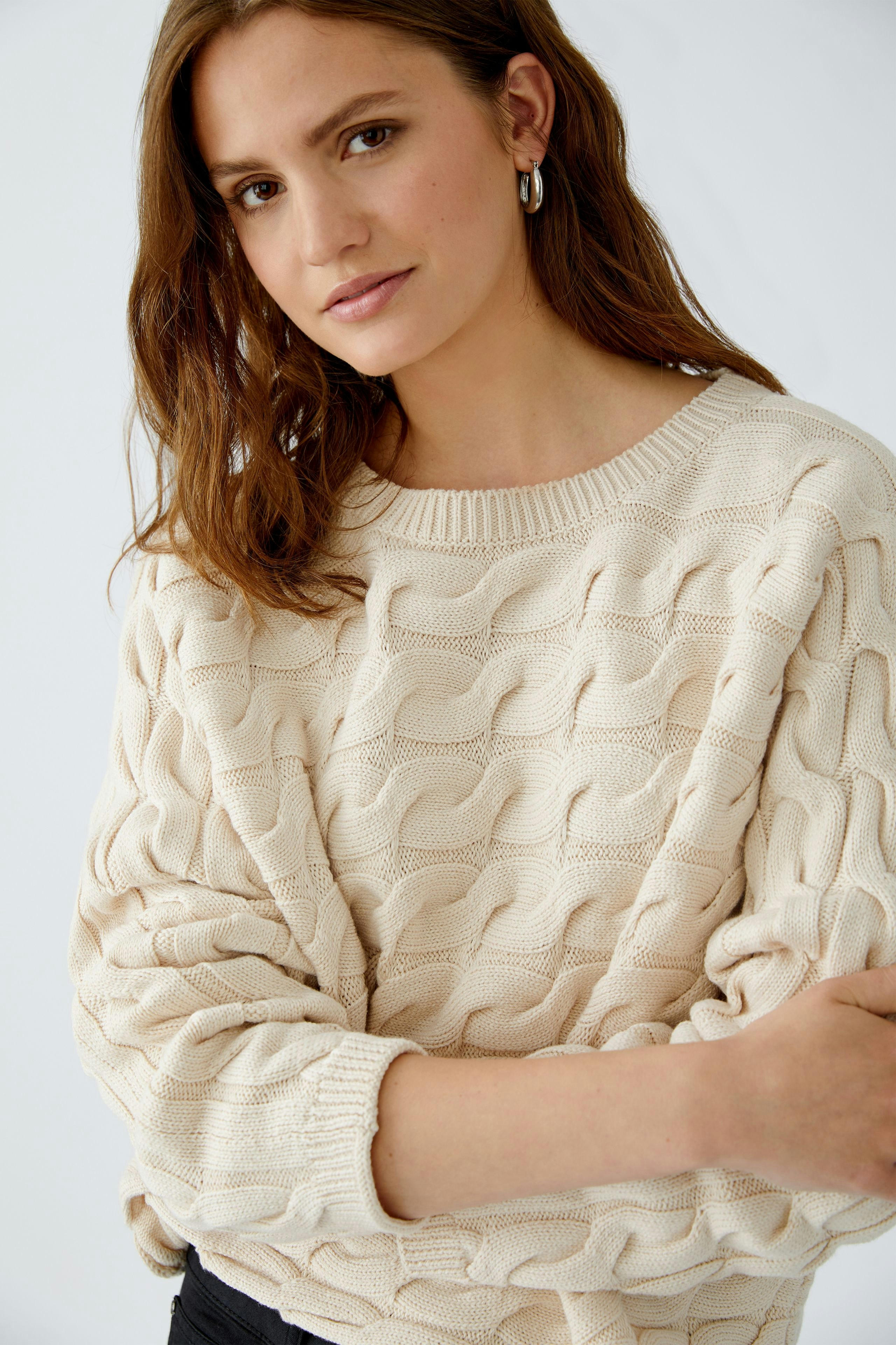 Beiger Damen-Pullover: Frau mit lässigem Strickpullover in Wellenstruktur, entspannt und modern.
