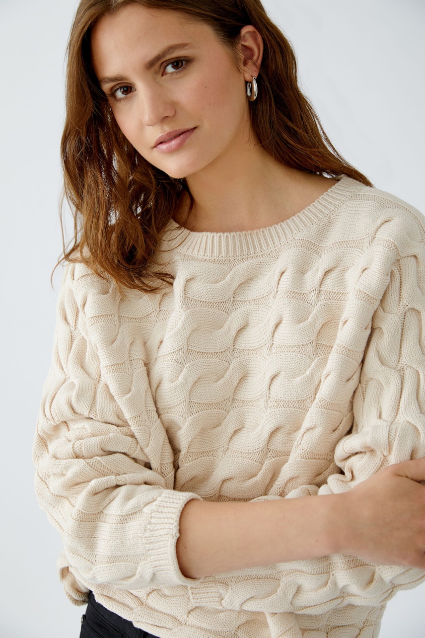 Casual women's pullover: A woman in a cream-colored textured pullover with a relaxed fit.