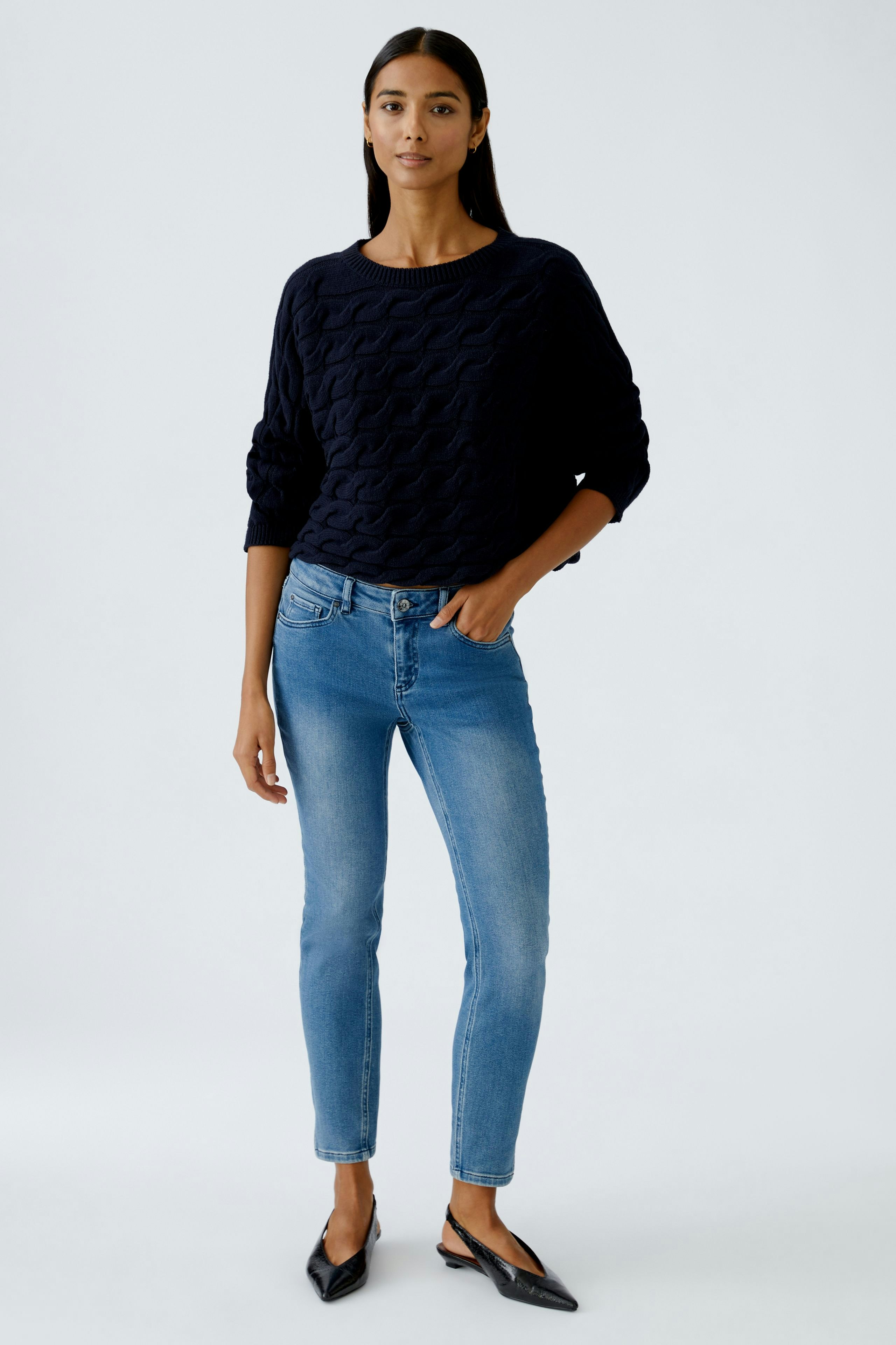 Casual women's pullover: Young woman in a navy textured pullover paired with light blue jeans.