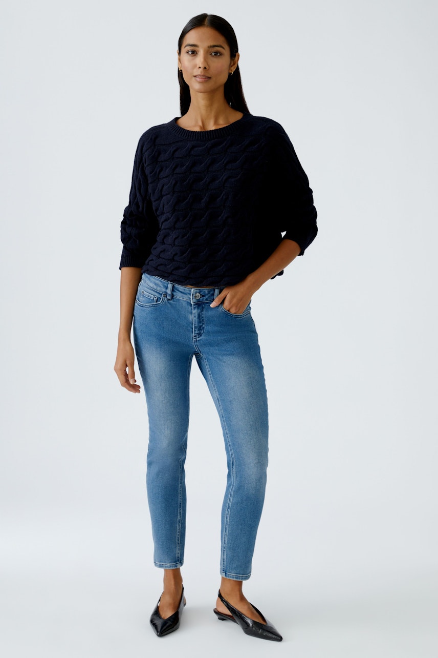 Damen-Pullover: Frau in dunkelblauem, strukturiertem Pullover mit lässigem Schnitt und Jeans.