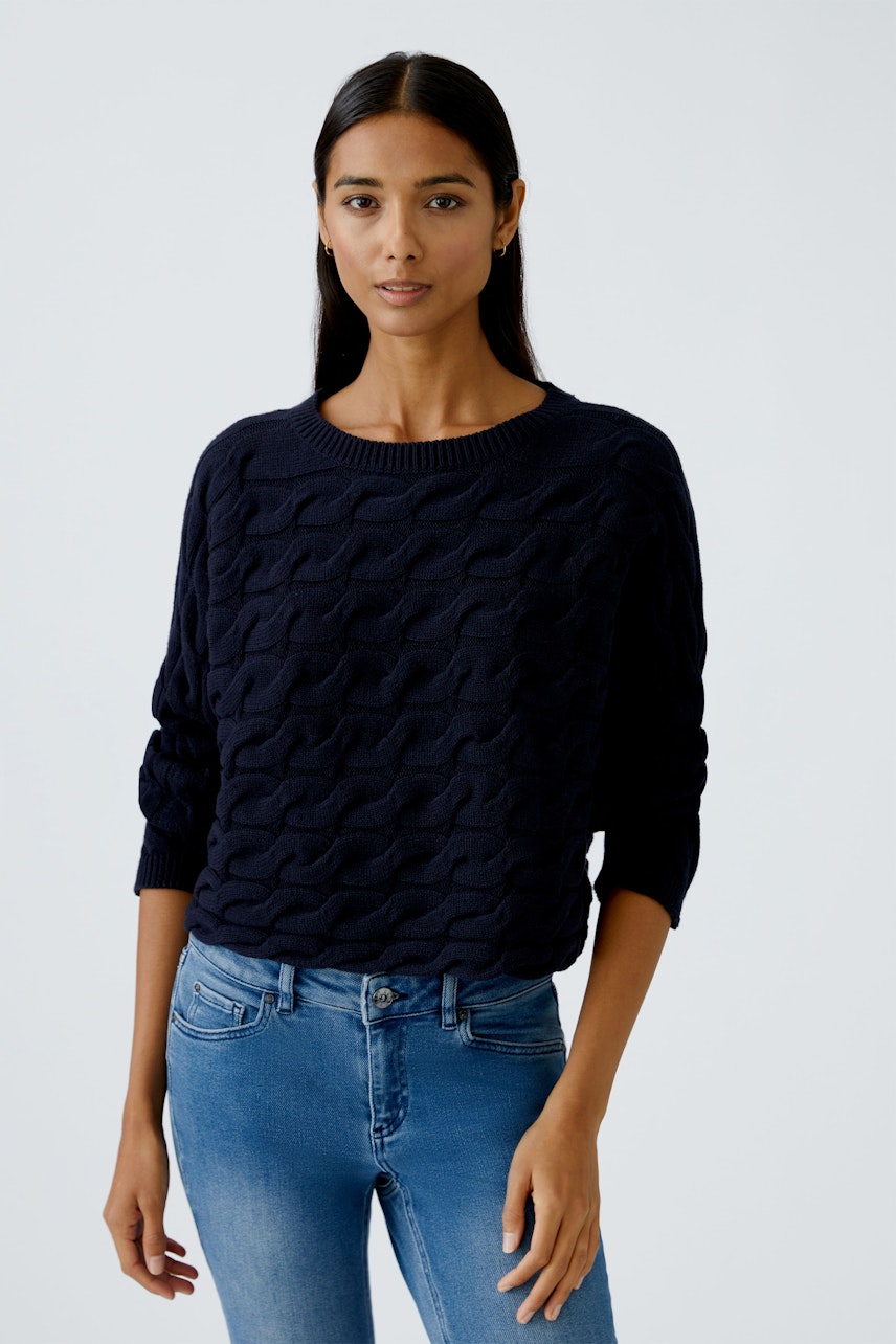 Damen-Pullover: Frau in dunkelblauem, strukturiertem Pullover mit Rundhalsausschnitt und lässigem Look.