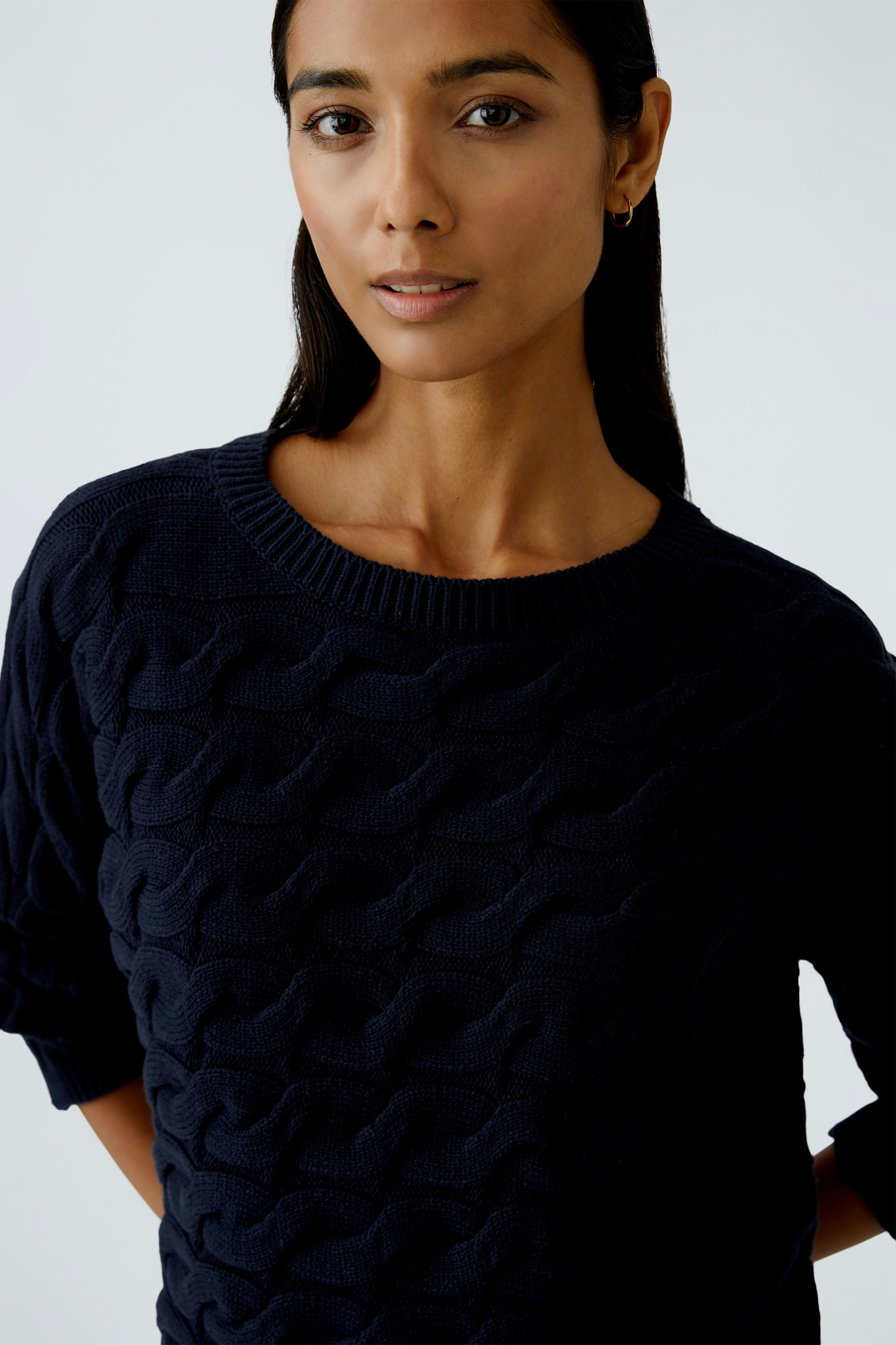 Casual women's pullover: Young woman in a navy knitted pullover with a textured pattern.