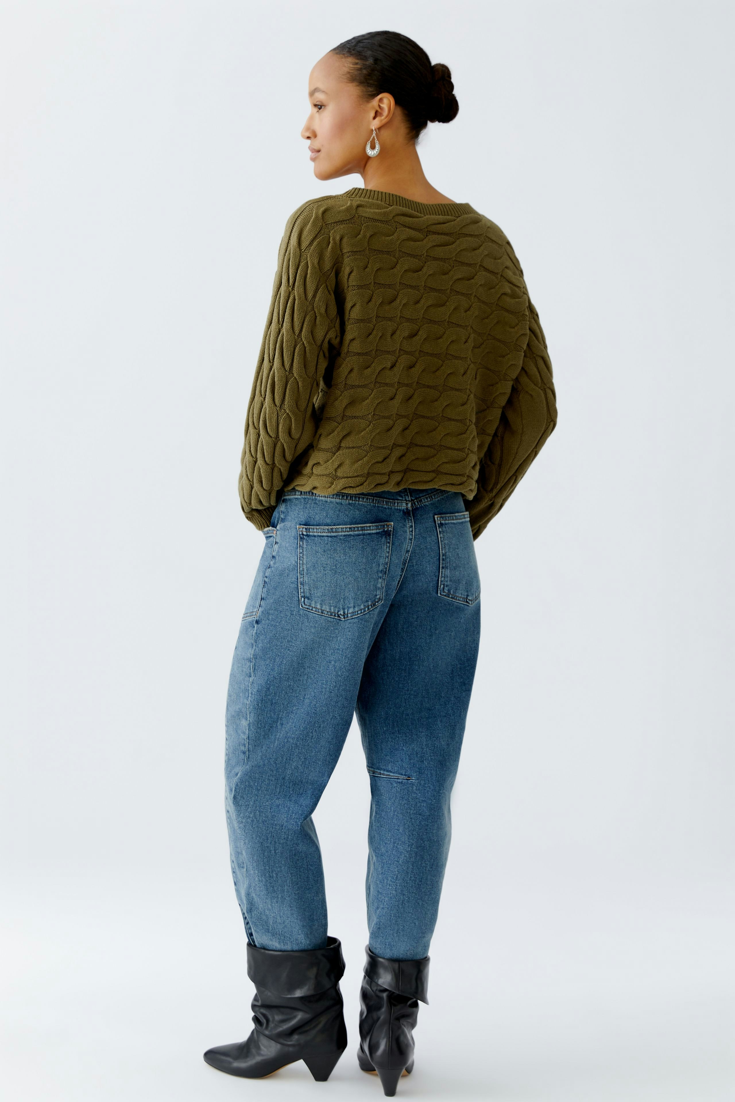 Casual women's pullover: A woman in a textured olive green pullover paired with relaxed jeans.