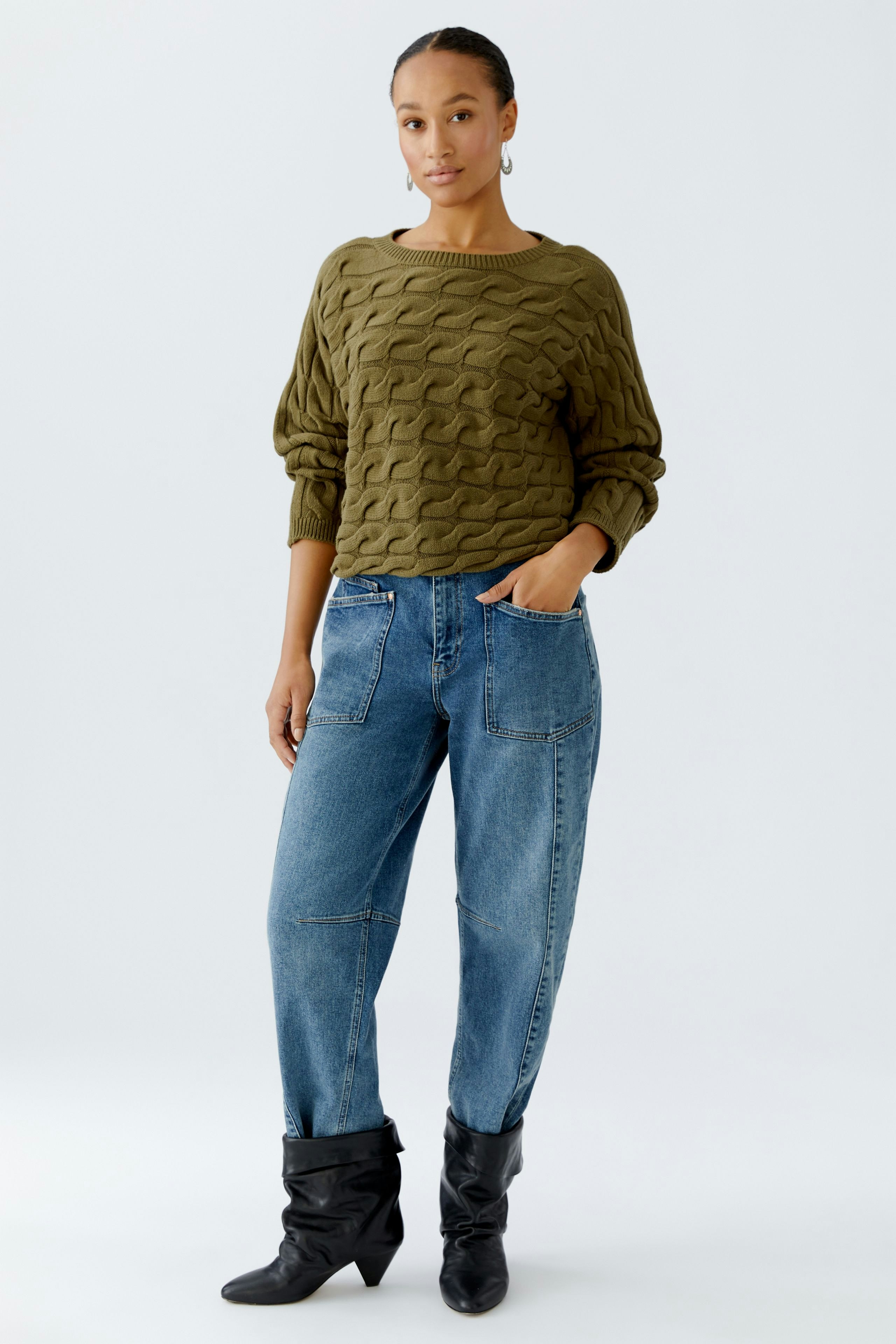 Casual women's pullover: A woman in an olive green textured pullover paired with relaxed-fit jeans.