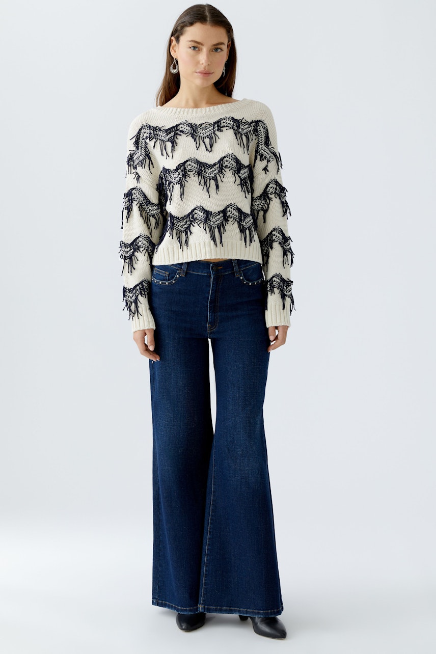 Damen Jeans Wide Leg: Frau trägt weite Jeans in Dunkelblau, kombiniert mit einem auffälligen Pullover.