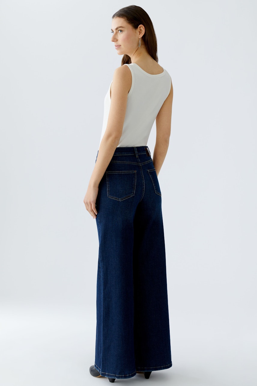 Damen Jeans Wide Leg: Frau trägt weite, dunkelblaue Jeans mit hohem Bund und lässigem Schnitt.