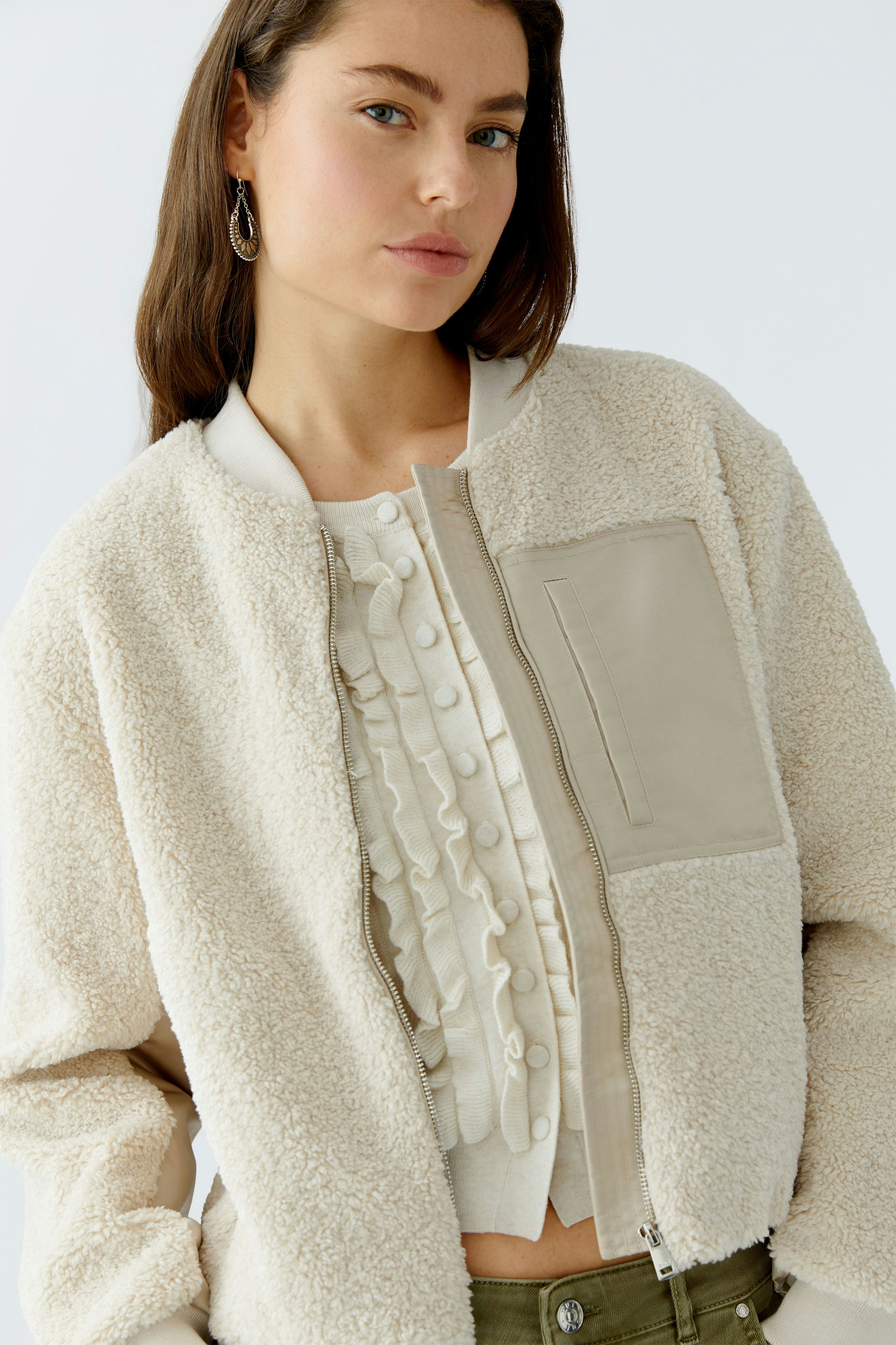Casual women's blouson: A woman in a cozy cream bomber jacket with a stylish front pocket.