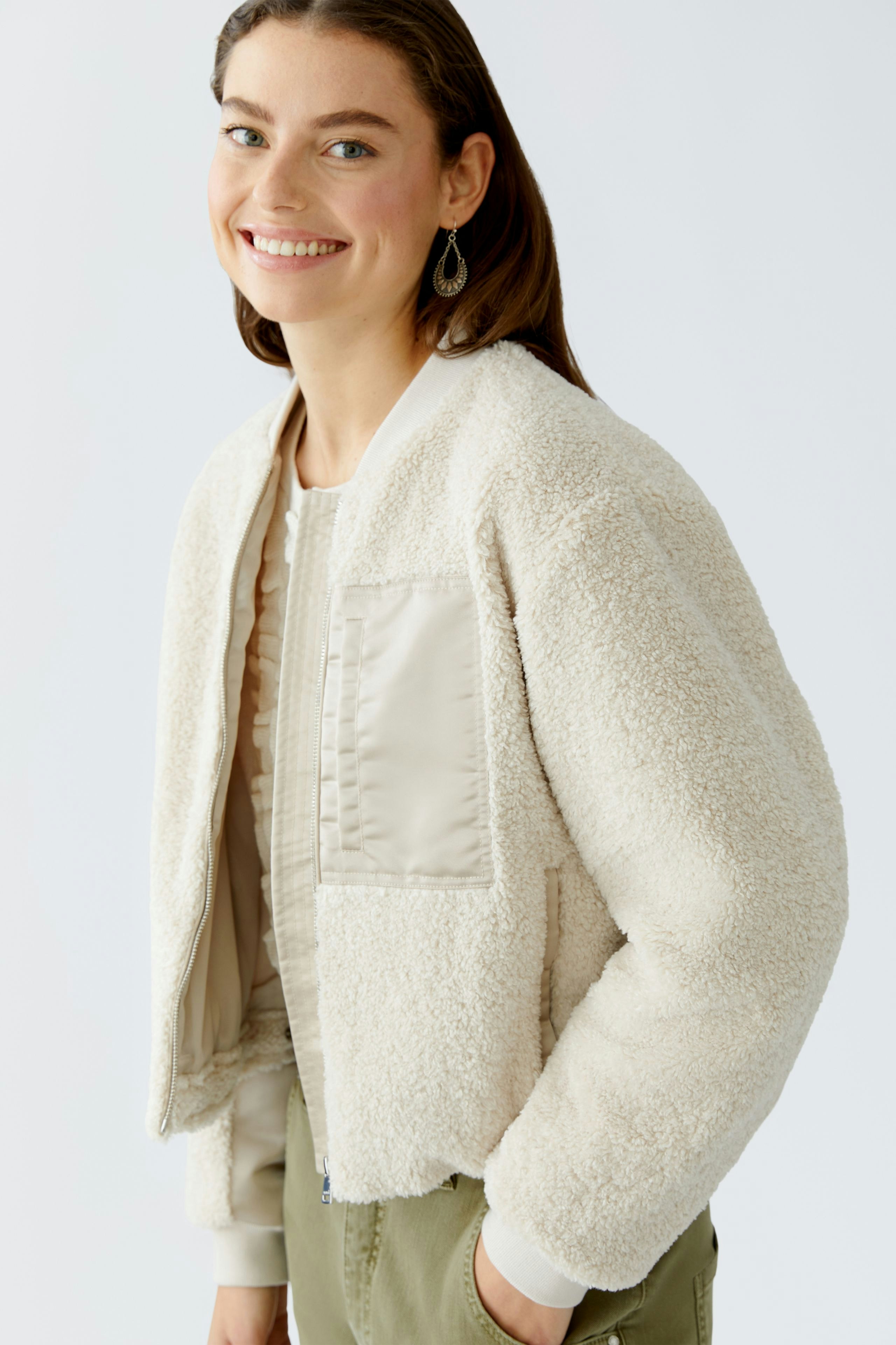 Casual women's blouson: Smiling woman in a cozy cream bomber jacket with a soft texture.