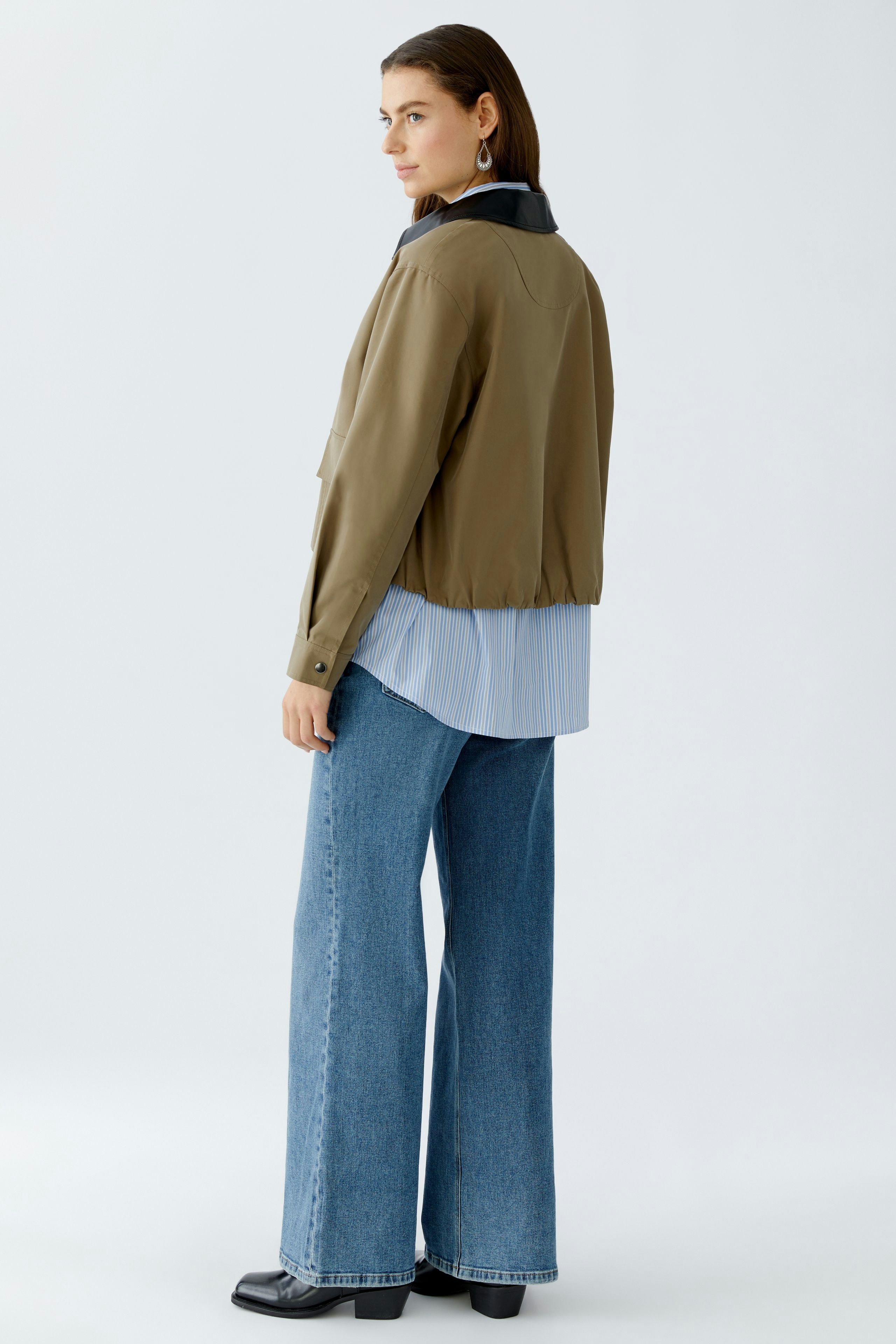 Damen-Jacke: Frau in lässiger, olivgrüner Jacke mit schwarzem Kragen und weitem Schnitt.