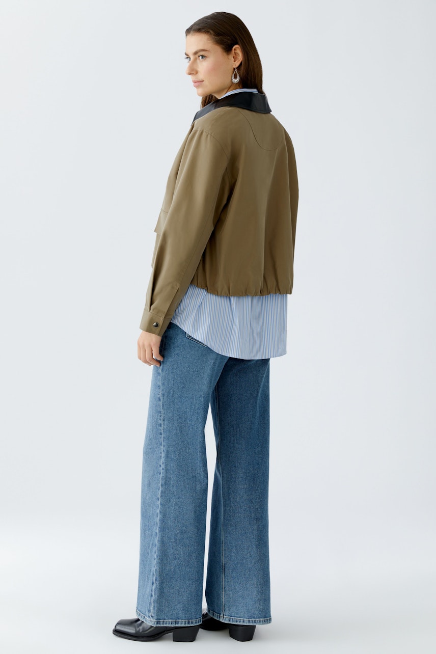 Damen-Jacke: Frau in lässiger, olivgrüner Jacke mit schwarzem Kragen und weitem Schnitt.