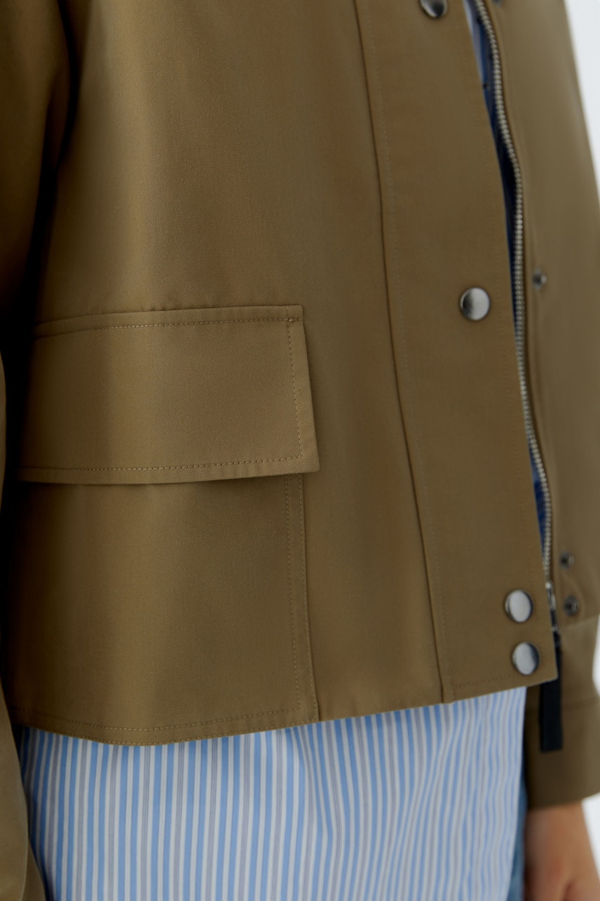 Damen-Jacke: Frau in olivgrüner Jacke mit praktischen Taschen und Reißverschluss.