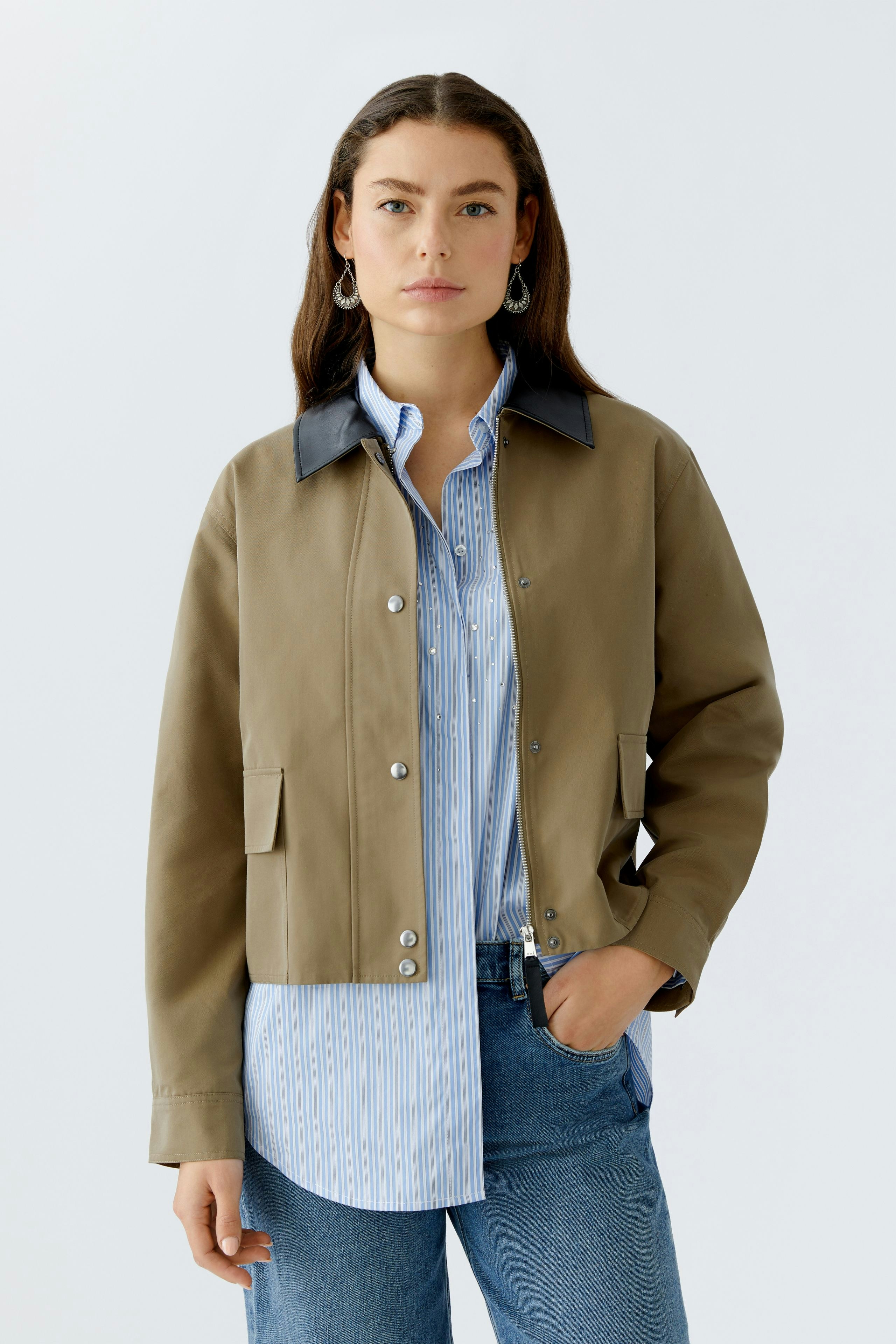 Damen-Jacke: Frau in beiger Jacke mit blauem Kragen und gestreifter Bluse, lässiger Look.