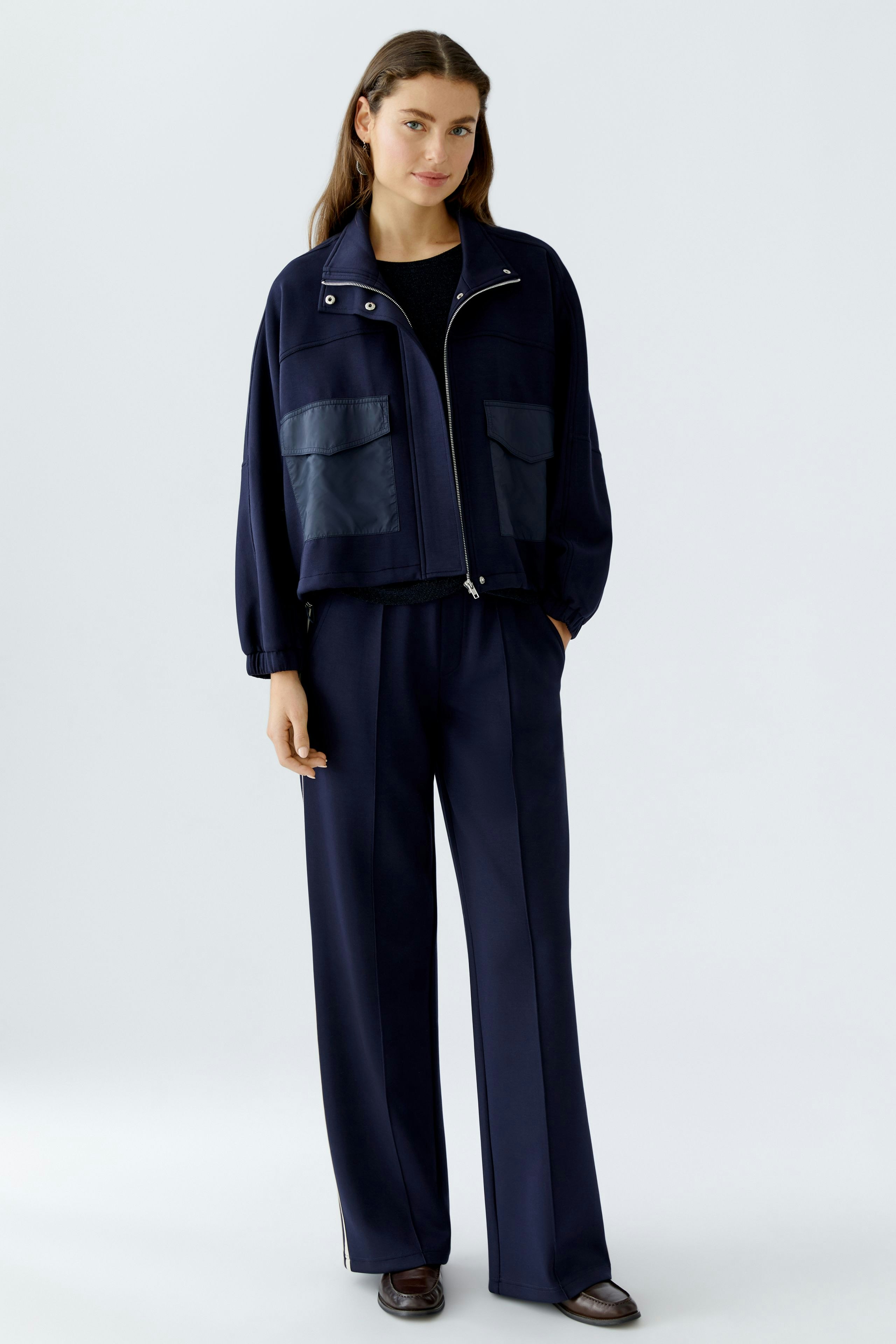 Casual women's jacket: A woman in a navy jacket with pockets, paired with matching pants.