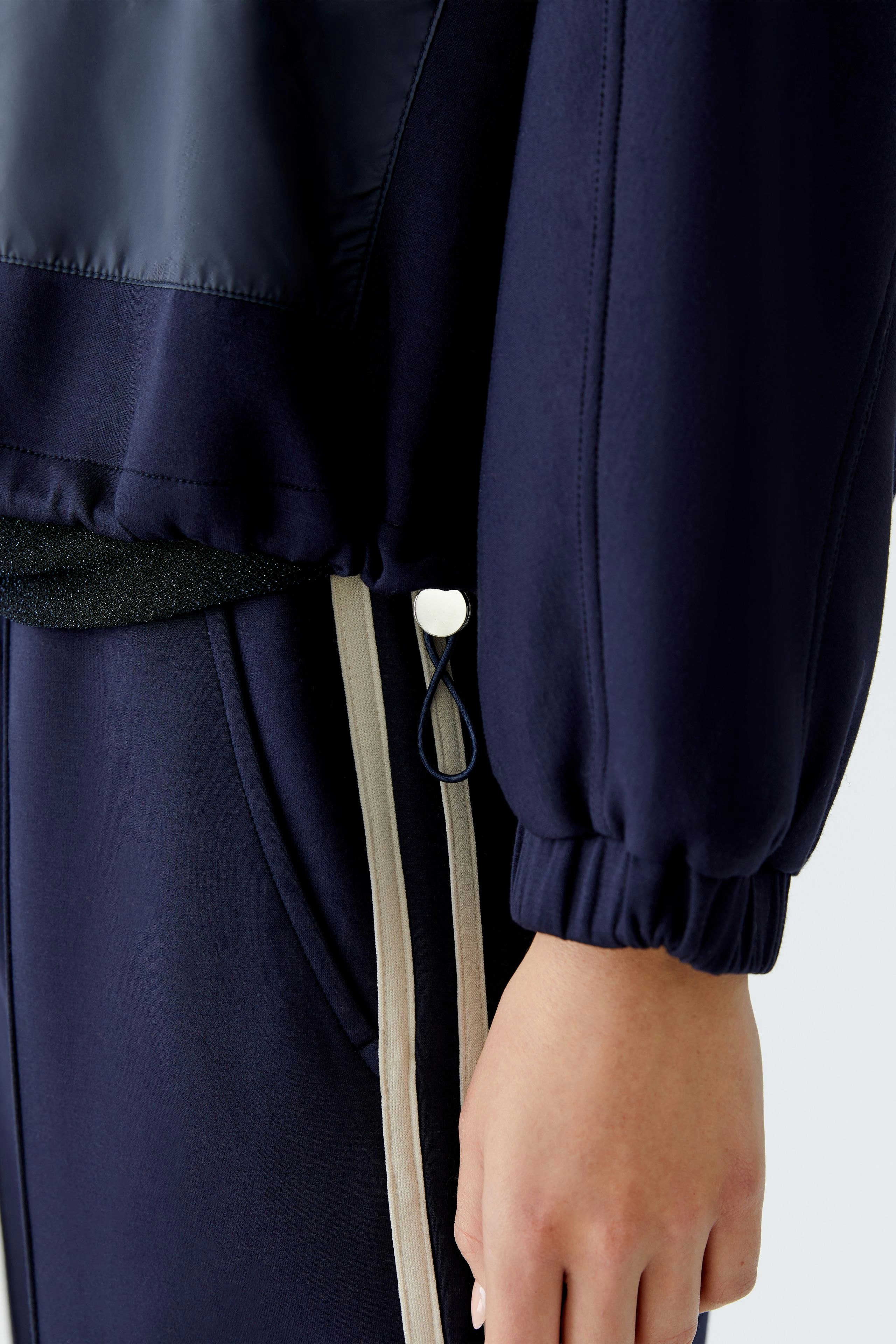 Casual women's jacket: Close-up of a woman wearing a navy jacket with elastic cuffs and sporty details.