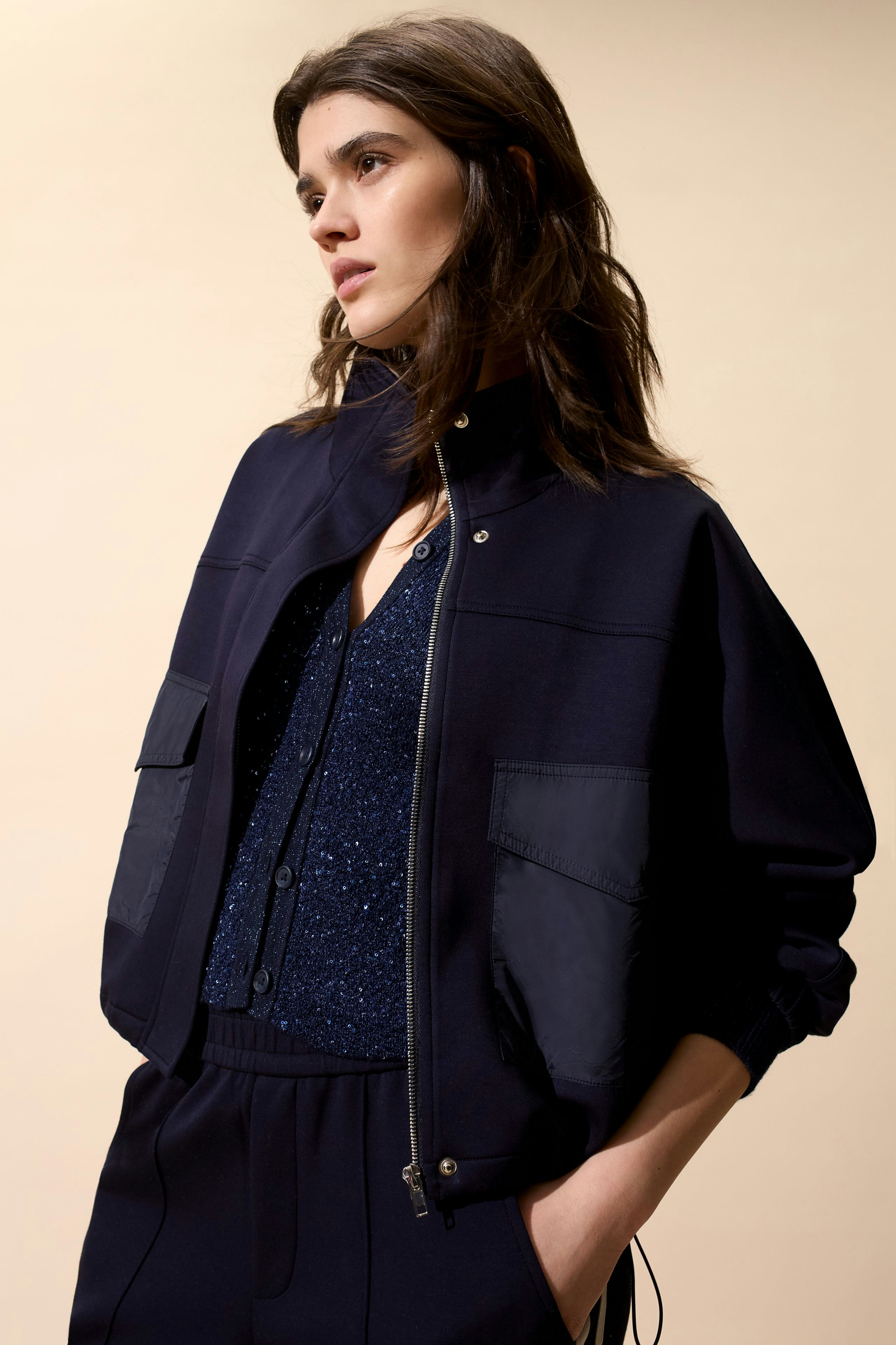 Casual women's jacket: Young woman in a navy jacket with pockets, styled with a sparkly top.