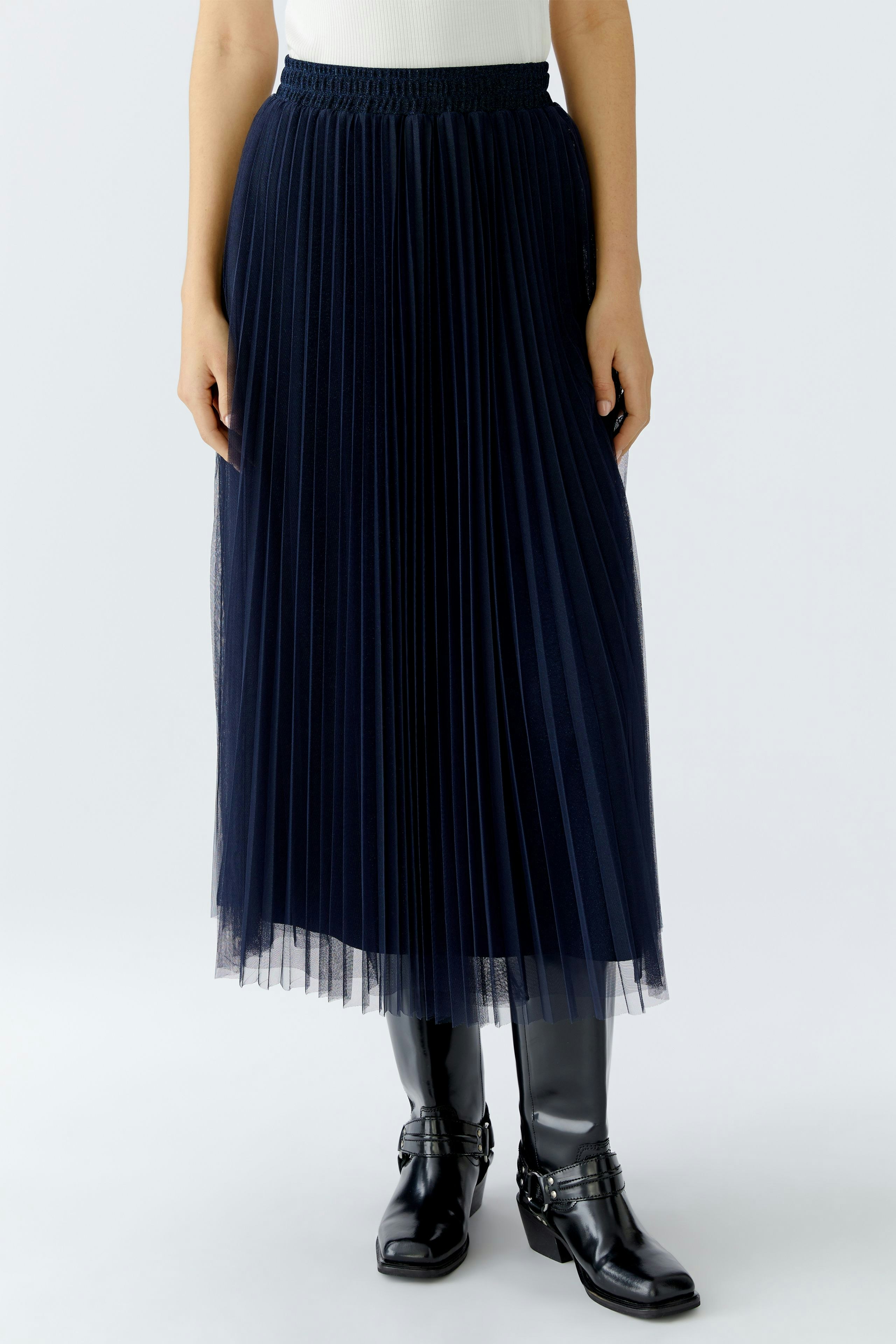 Damen-Plisseerock: Frau trägt einen langen, dunkelblauen Plisseerock mit elastischem Bund und Stiefeln.