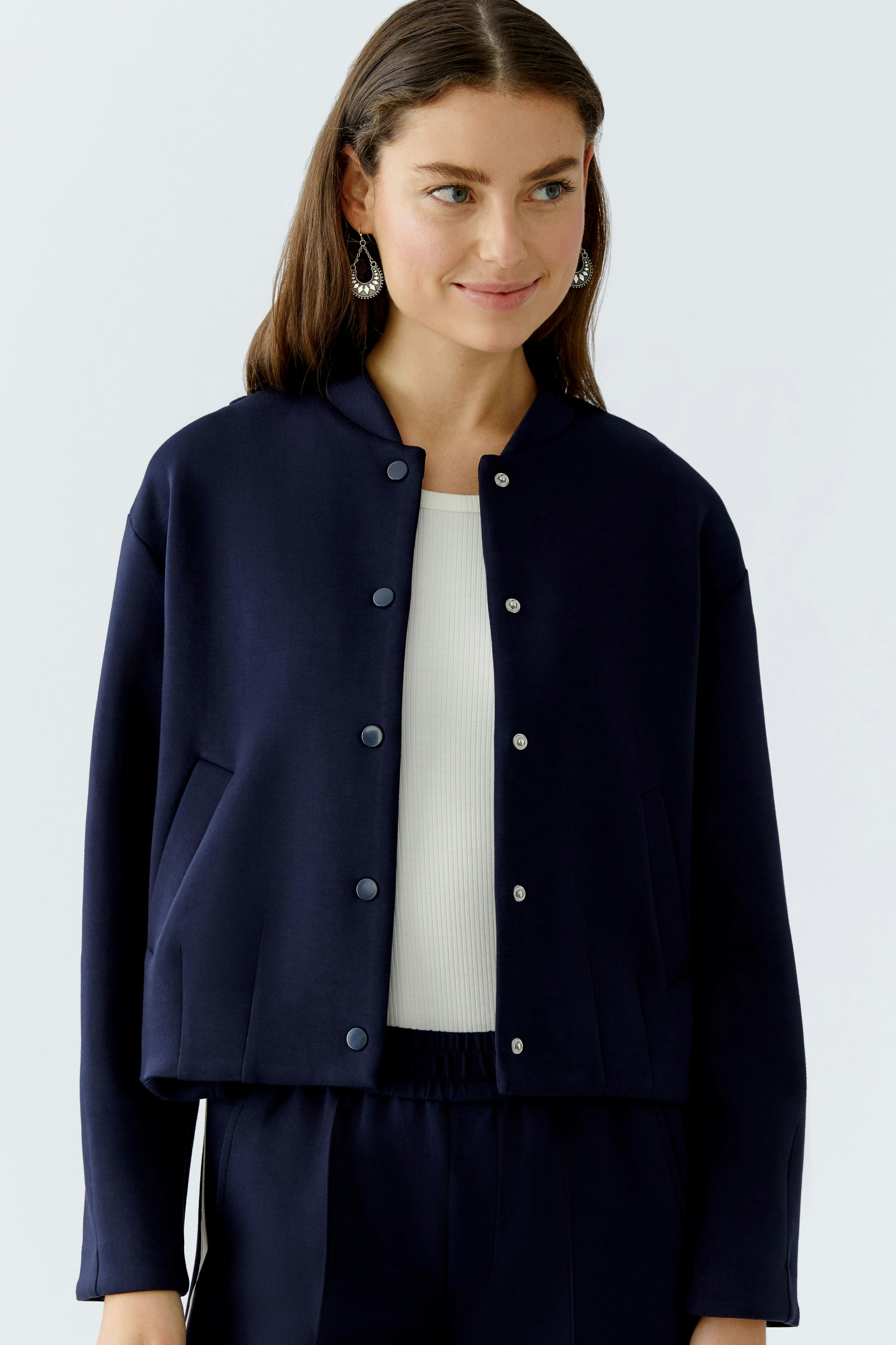 Damen-Blouson: Junge Frau in dunkelblauer Bomberjacke mit Druckknöpfen und lässigem Look.