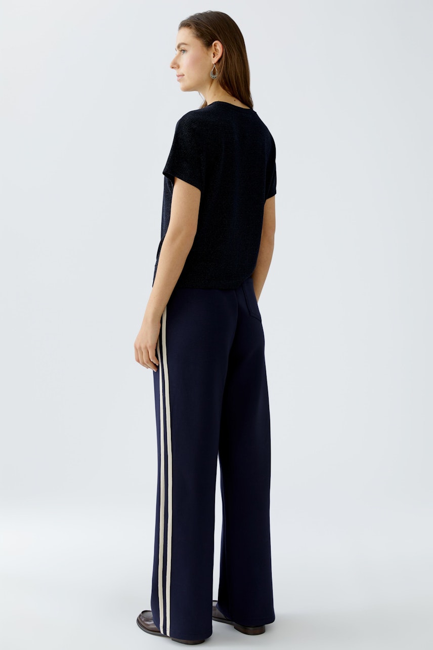 Casual women's T-shirt: A woman in a black T-shirt paired with wide-leg pants, showcasing a relaxed style.