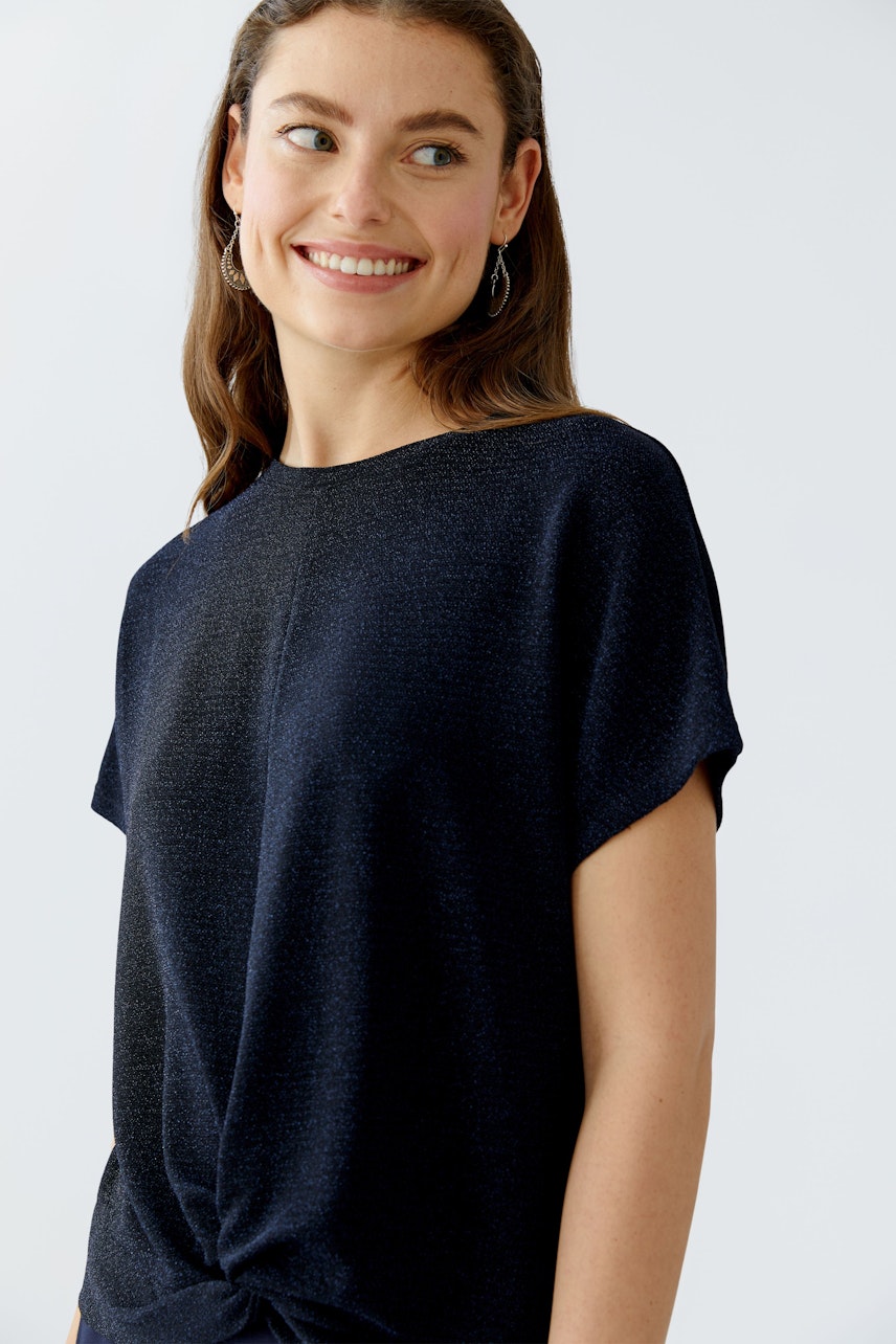 Casual women's T-shirt: Smiling woman in a dark blue top with a knotted detail.