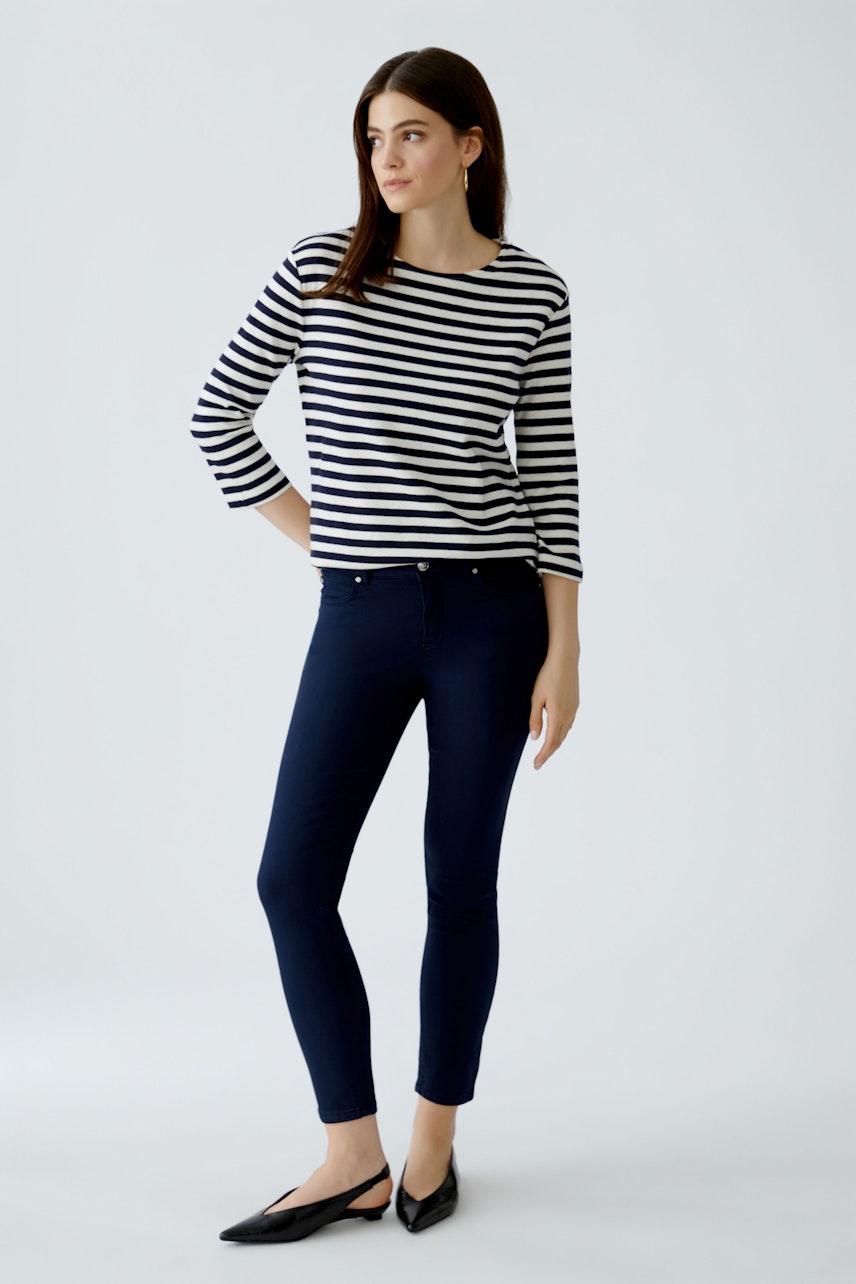 Damen-T-Shirt: Frau in gestreiftem Shirt mit 3/4-Ärmeln und schmalen Jeans, lässiger Look.
