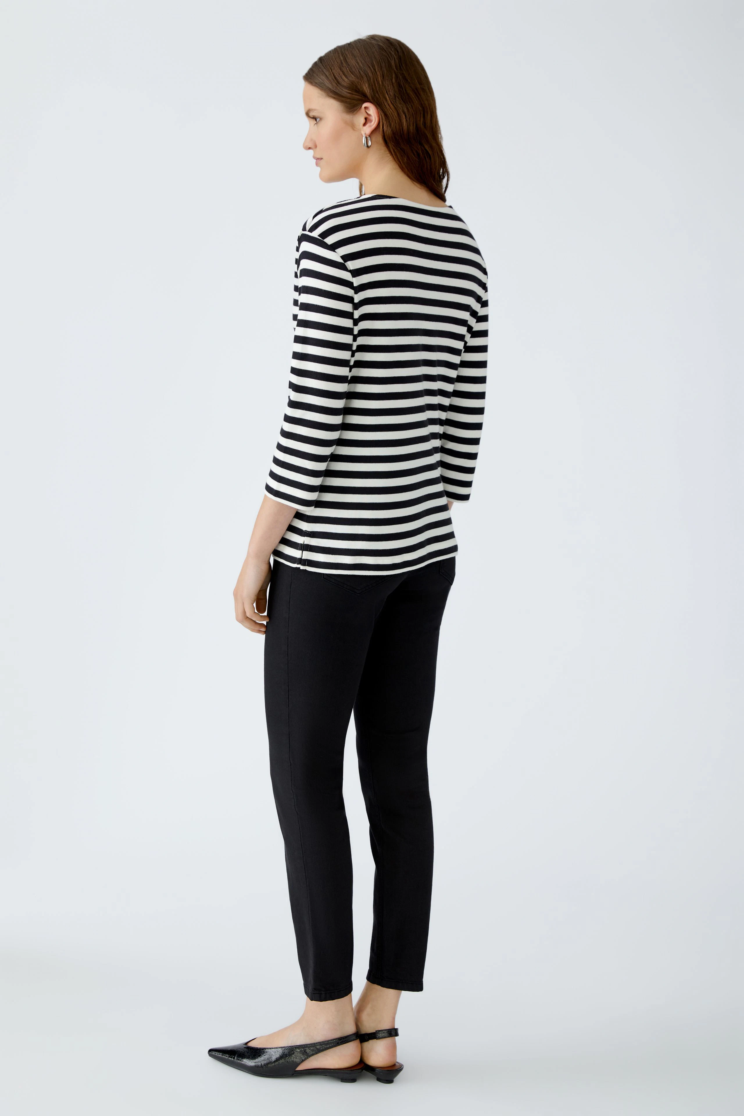 Casual women's T-shirt: Young woman in a striped top and black pants, showcasing a relaxed style.