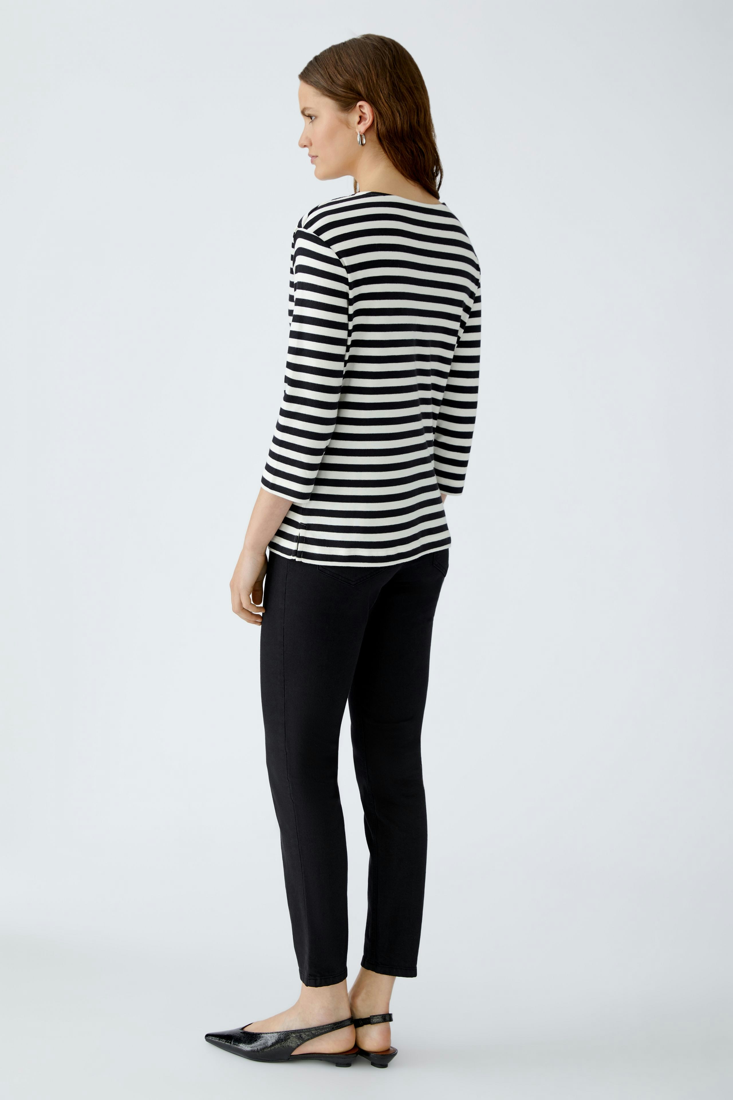 Casual women's T-shirt: Young woman in a striped top and black pants, showcasing a relaxed style.