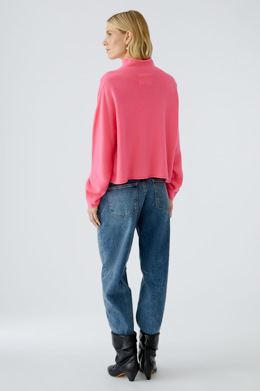 Damen-Pullover: Frau trägt einen pinken, lässigen Pullover mit weitem Schnitt und kombiniert ihn mit Jeans.