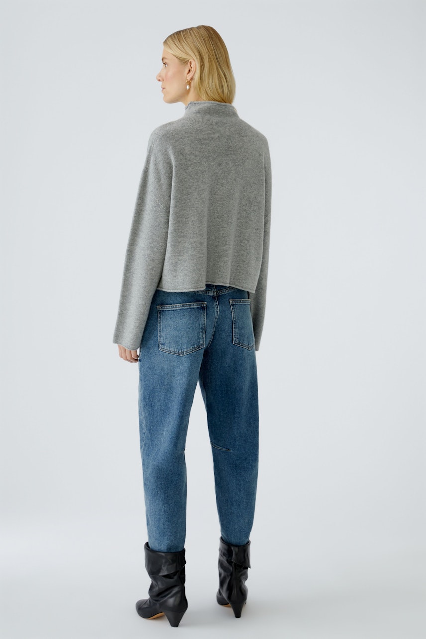 Damen-Pullover: Frau in grauem, lässigem Strickpullover mit lockerer Passform und Jeans.