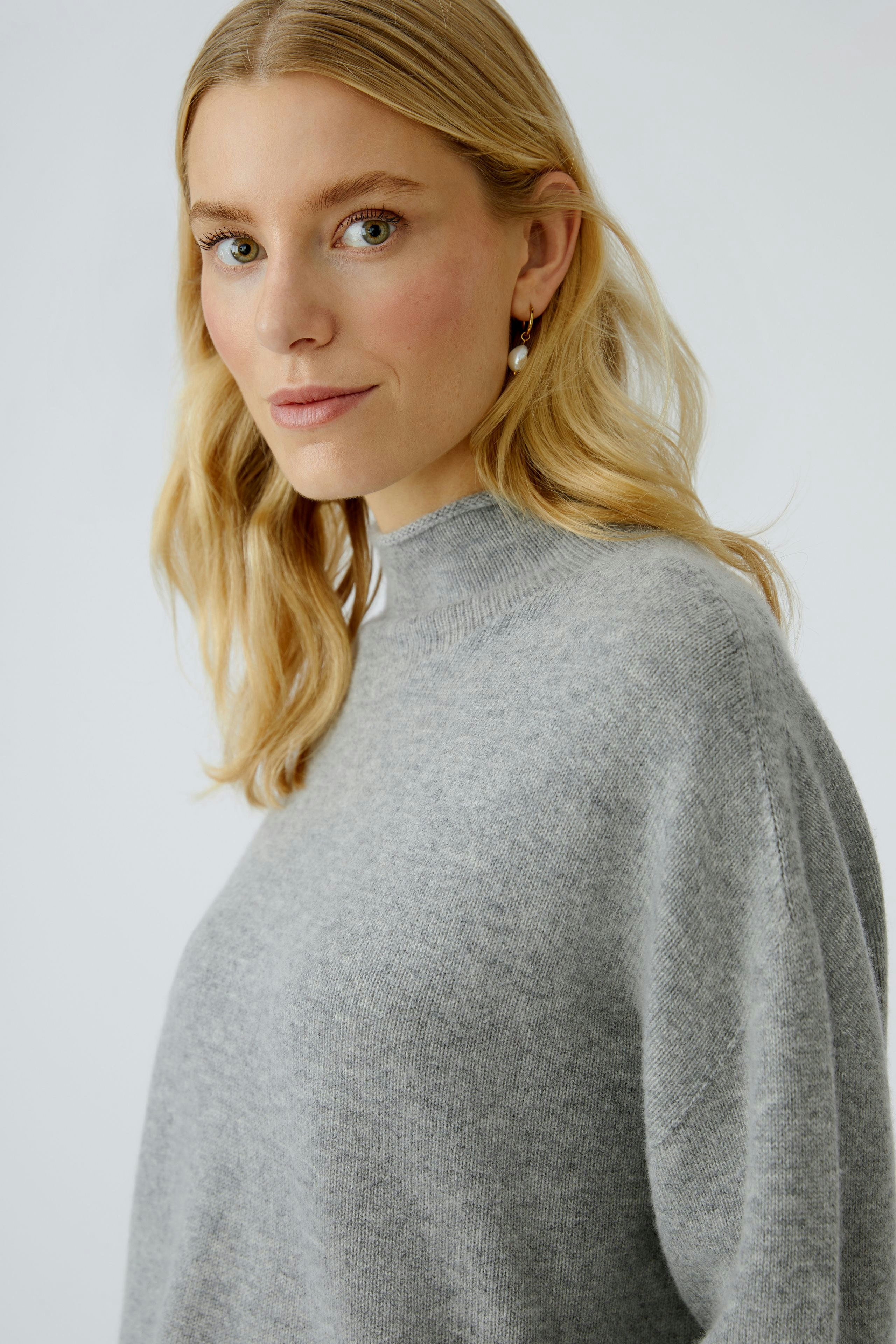 Damen-Pullover: Frau in grauem, lässigem Pullover mit hohem Kragen und lockerer Passform.