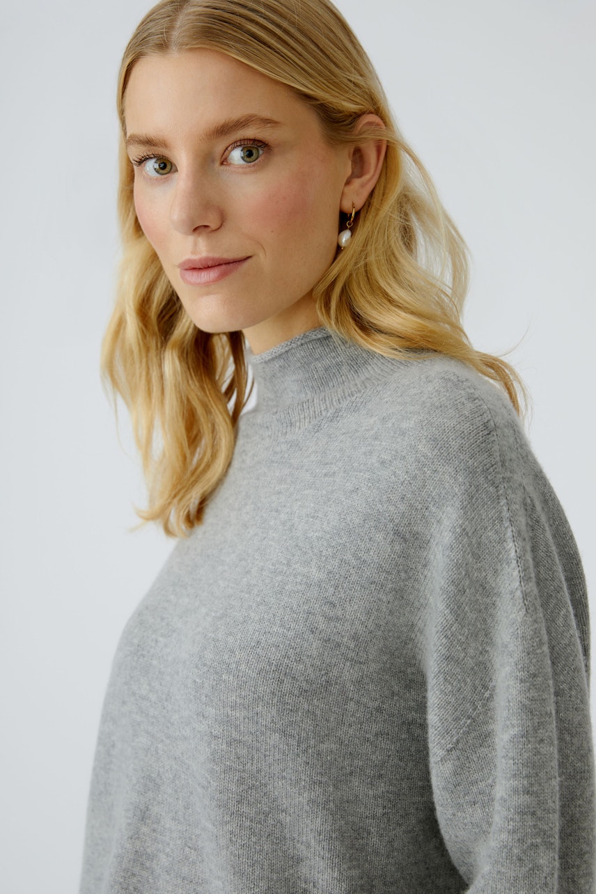 Damen-Pullover: Frau in grauem, lässigem Pullover mit hohem Kragen und lockerer Passform.