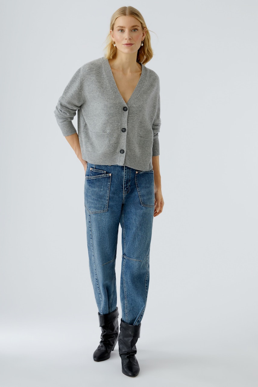 Bequeme Damen-Strickjacke: Frau in grauer Strickjacke mit Knöpfen und lässigen Jeans.