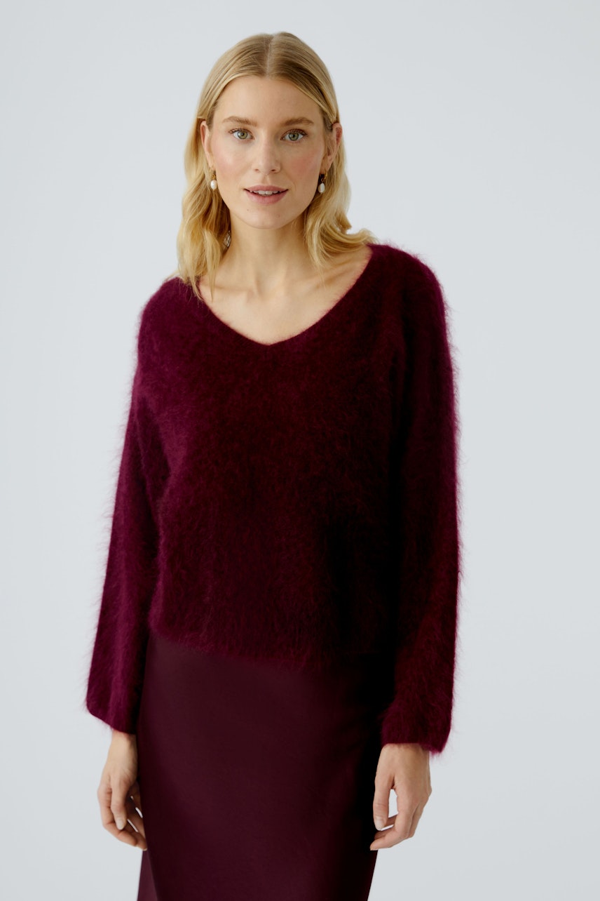 Cozy women's pullover: A woman in a soft, burgundy pullover with a relaxed fit and v-neck.
