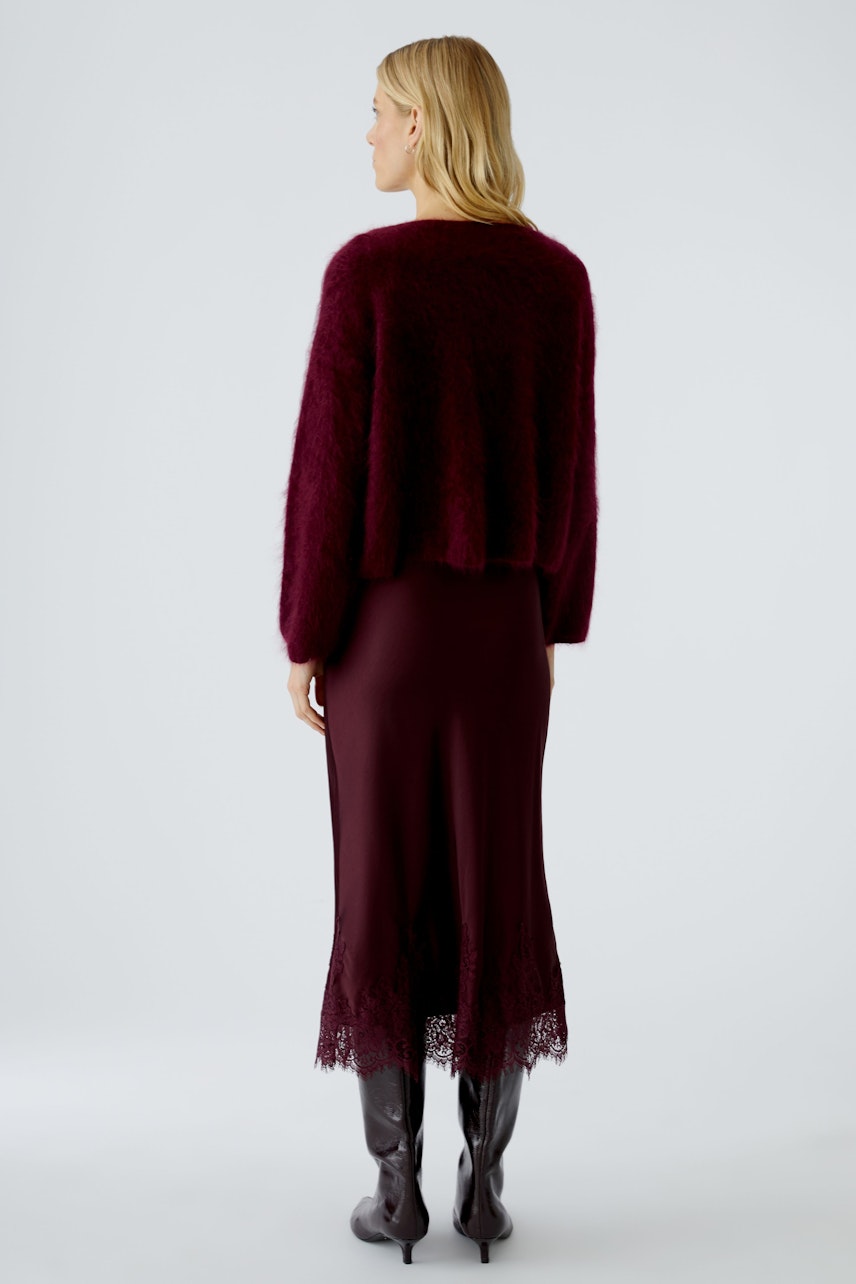Cozy women's pullover in deep burgundy, paired with a sleek dress, showcasing a relaxed style.