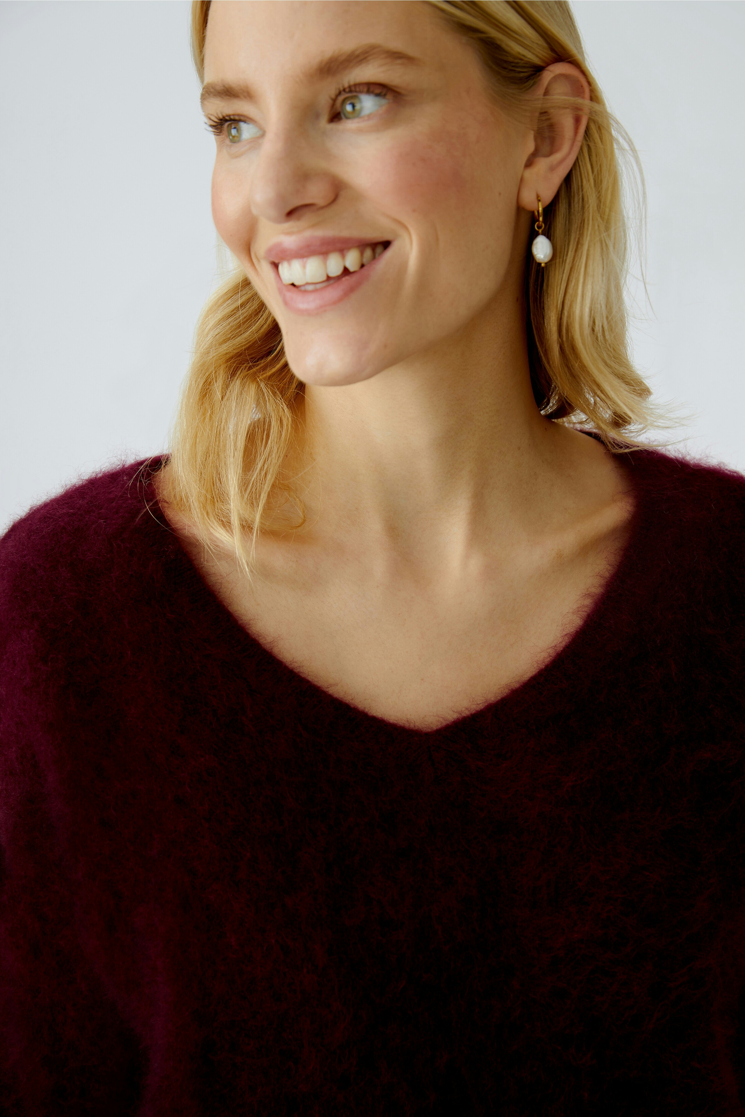 Casual women's pullover: Smiling woman in a deep burgundy fluffy pullover with a V-neck.