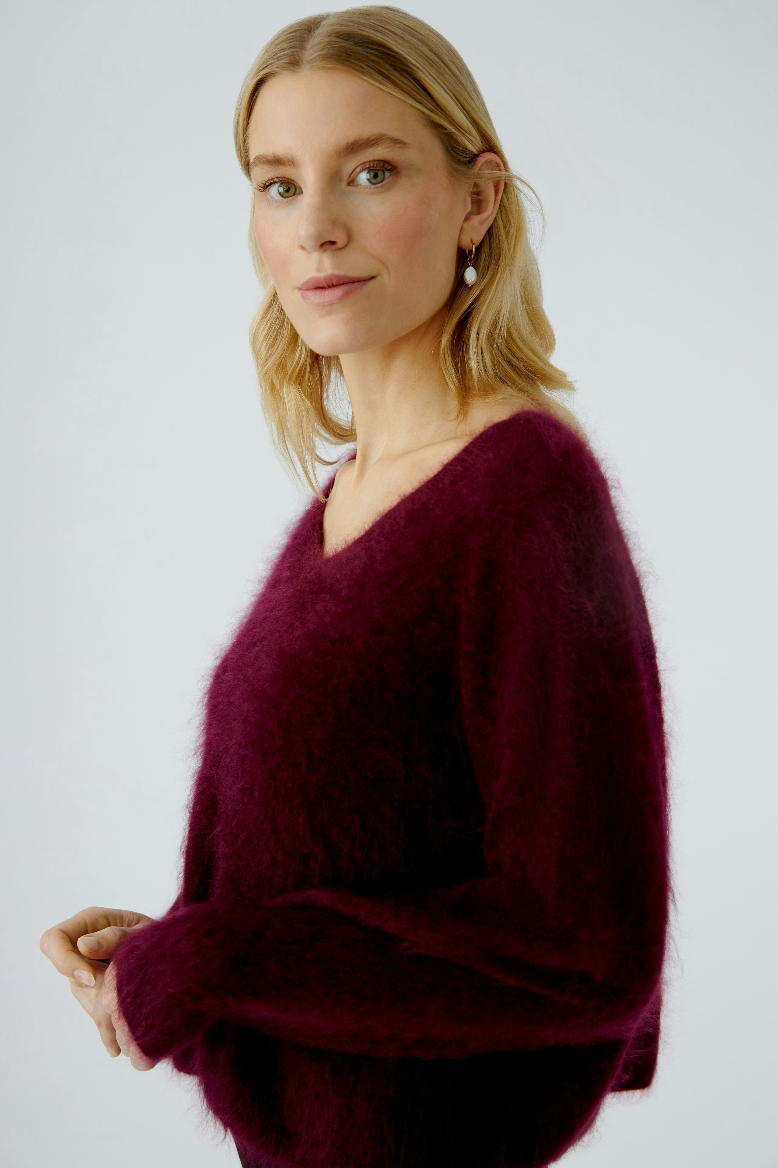 Cozy women's pullover: A woman in a soft, deep purple pullover with a relaxed fit.