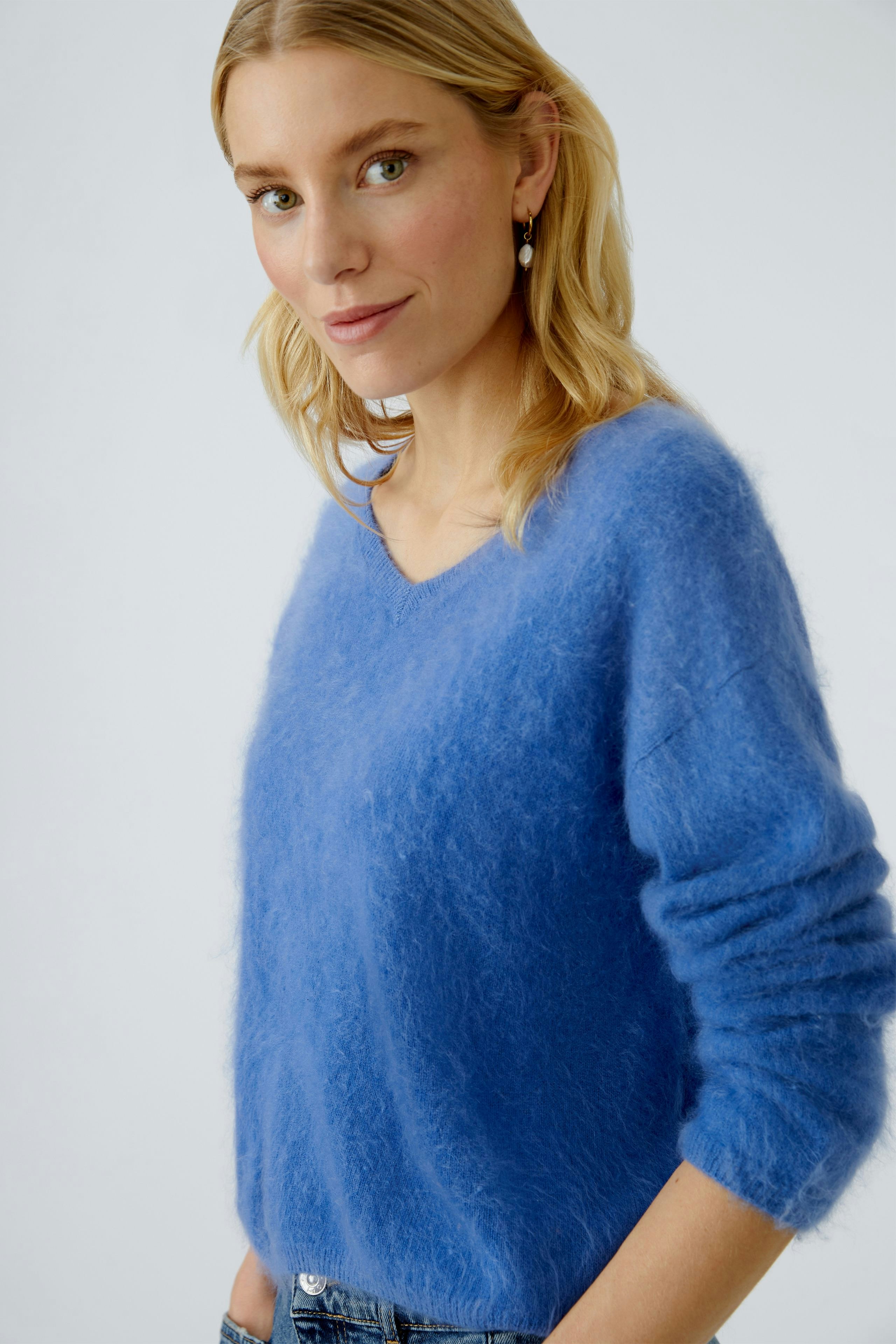 Casual women's pullover: Young woman in a soft blue pullover with a relaxed fit, smiling confidently.