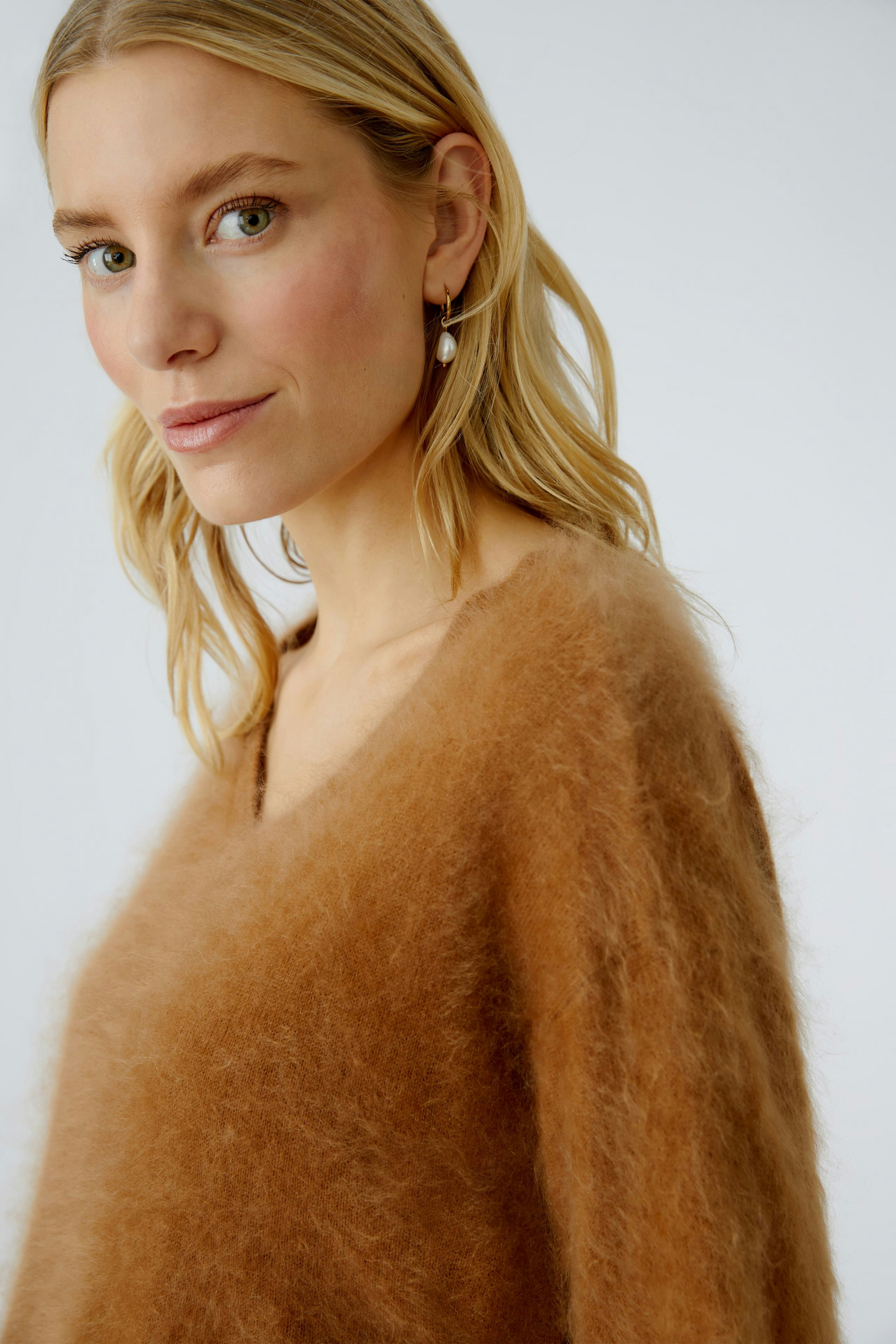 Modern women's pullover: A woman in a soft brown pullover with a relaxed fit and V-neck.